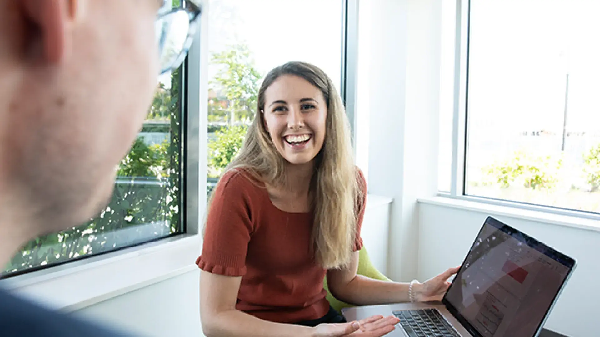 Woman gestures to laptop in questioning fashion to man in foreground