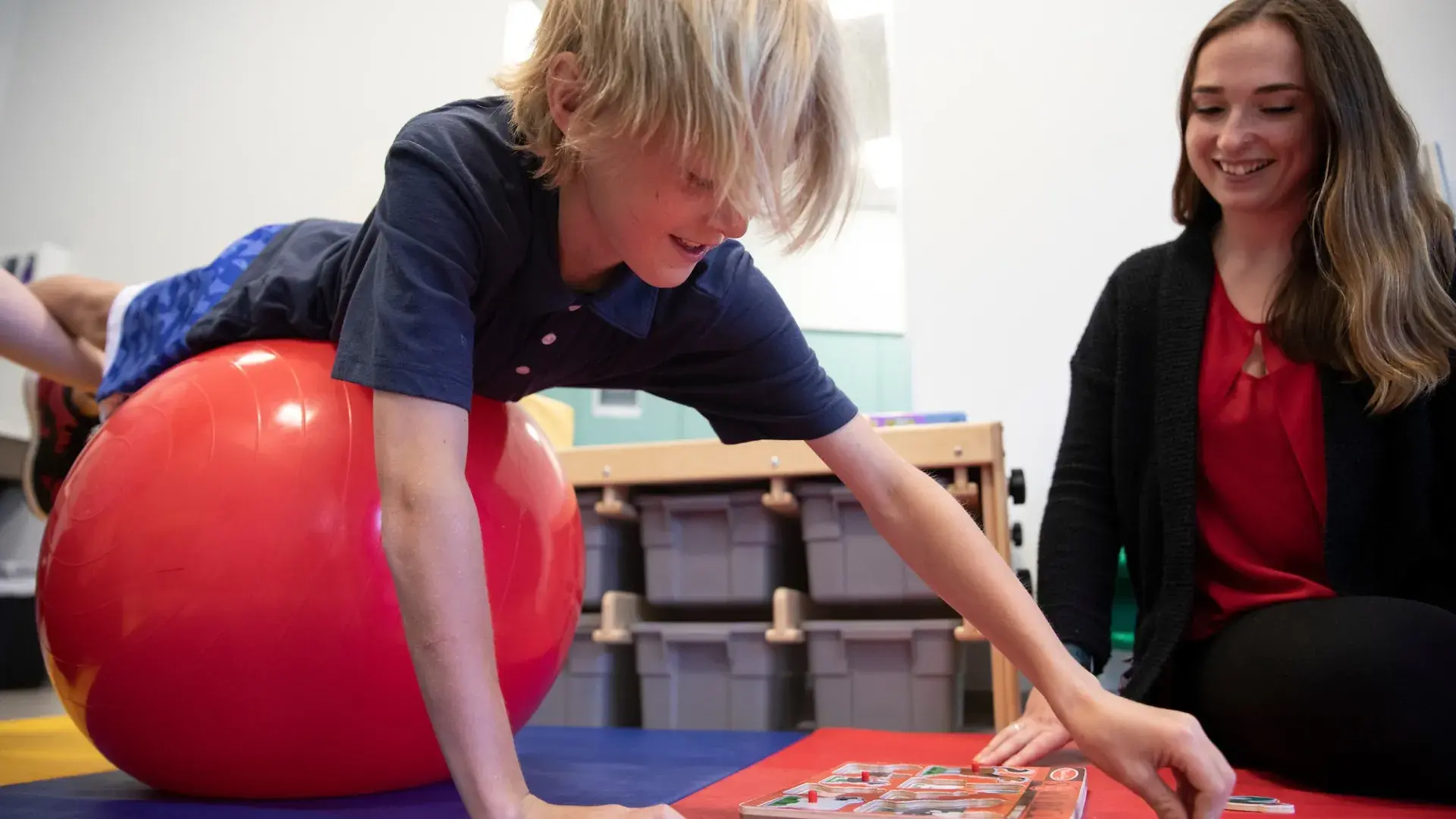 Occupational therapy student assisting a child during therapy using a stability ball and educational game in the Doctor of Occupational Therapy program.