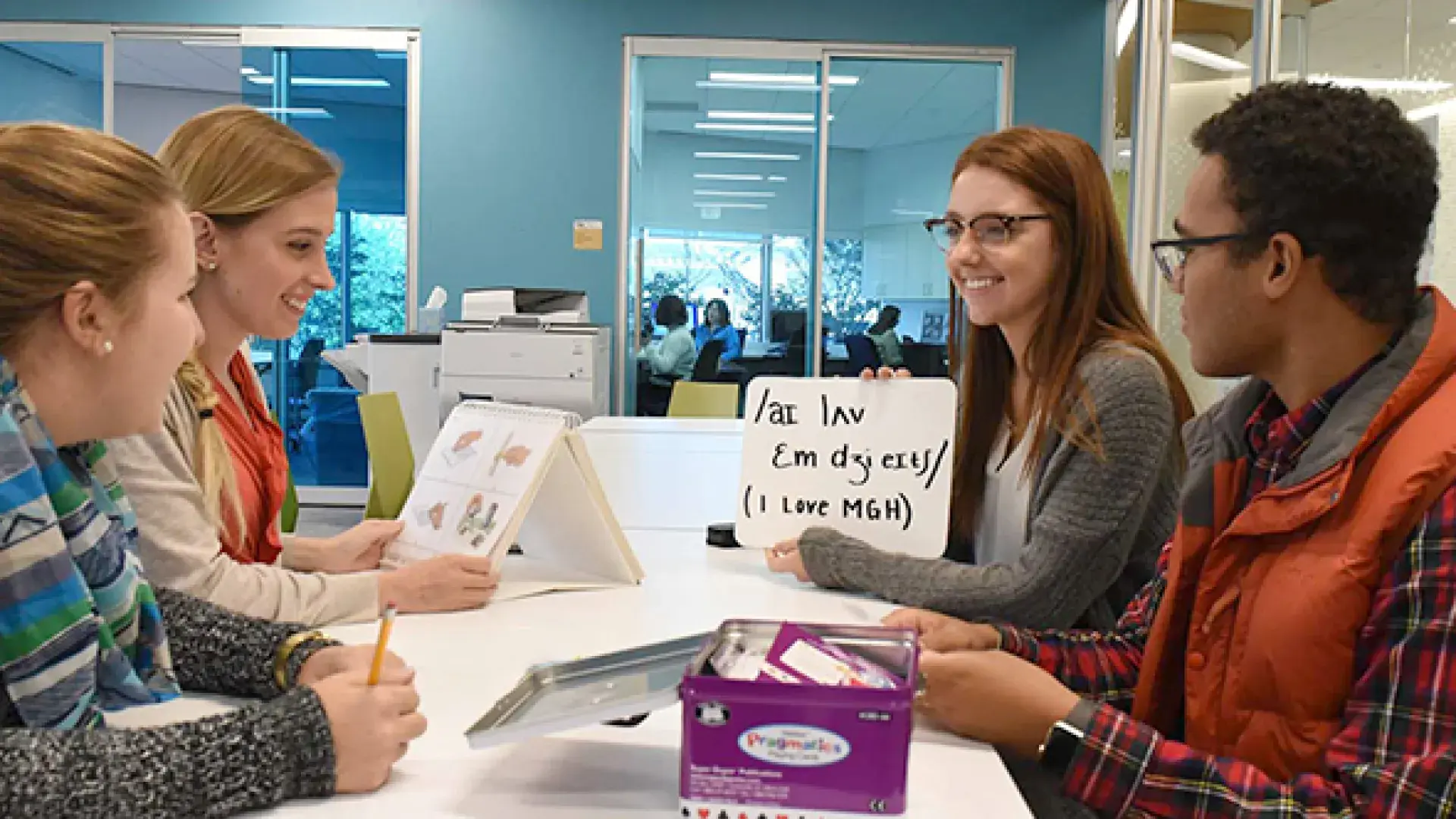 4 students sit at a table and look at words on a card