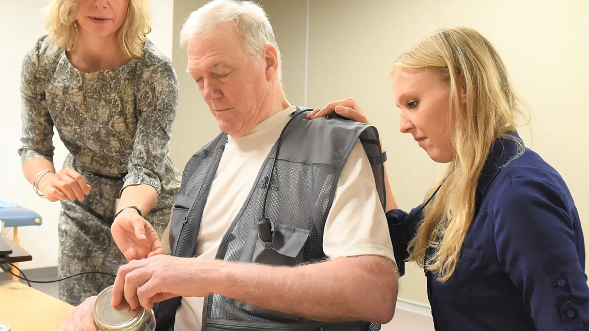 Photo of Dr. Teresa Kimberley (left) works with a patient (center) and a grad assistant at the Brain Recovery Lab on the MGH Institute campus.