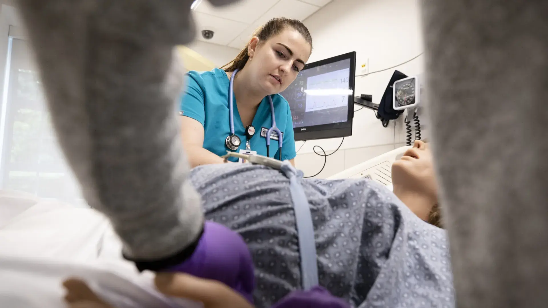 woman in scrubs examines a pregnant manikin