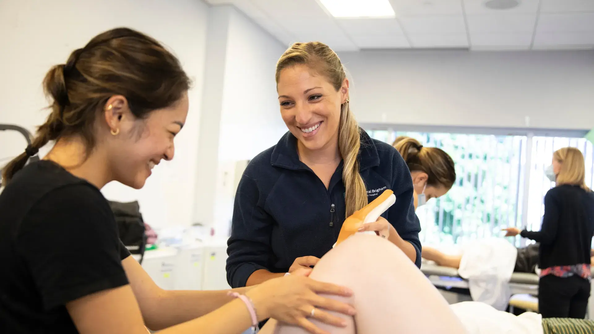 two students look at a person's knee and compare it to a plastic model of a knee