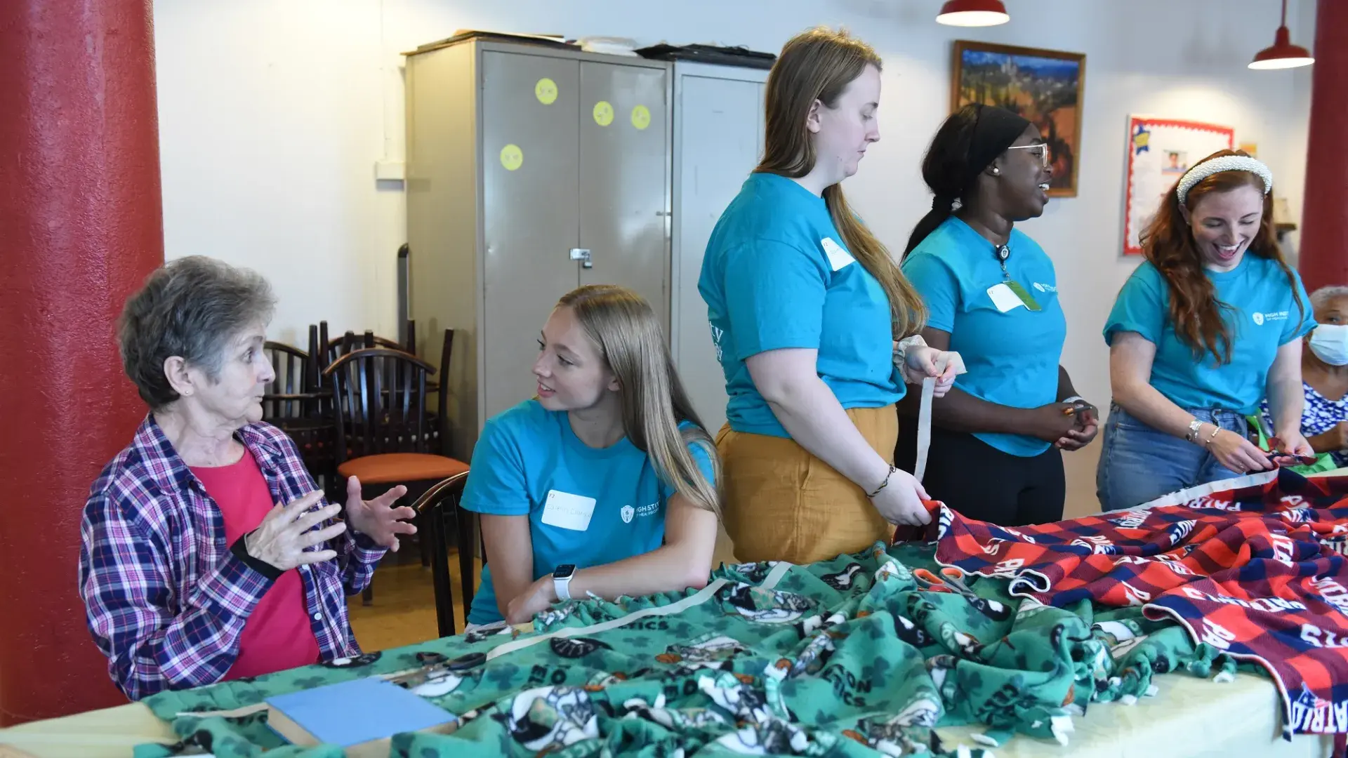 students smile and chat while at a table with fleece blankets