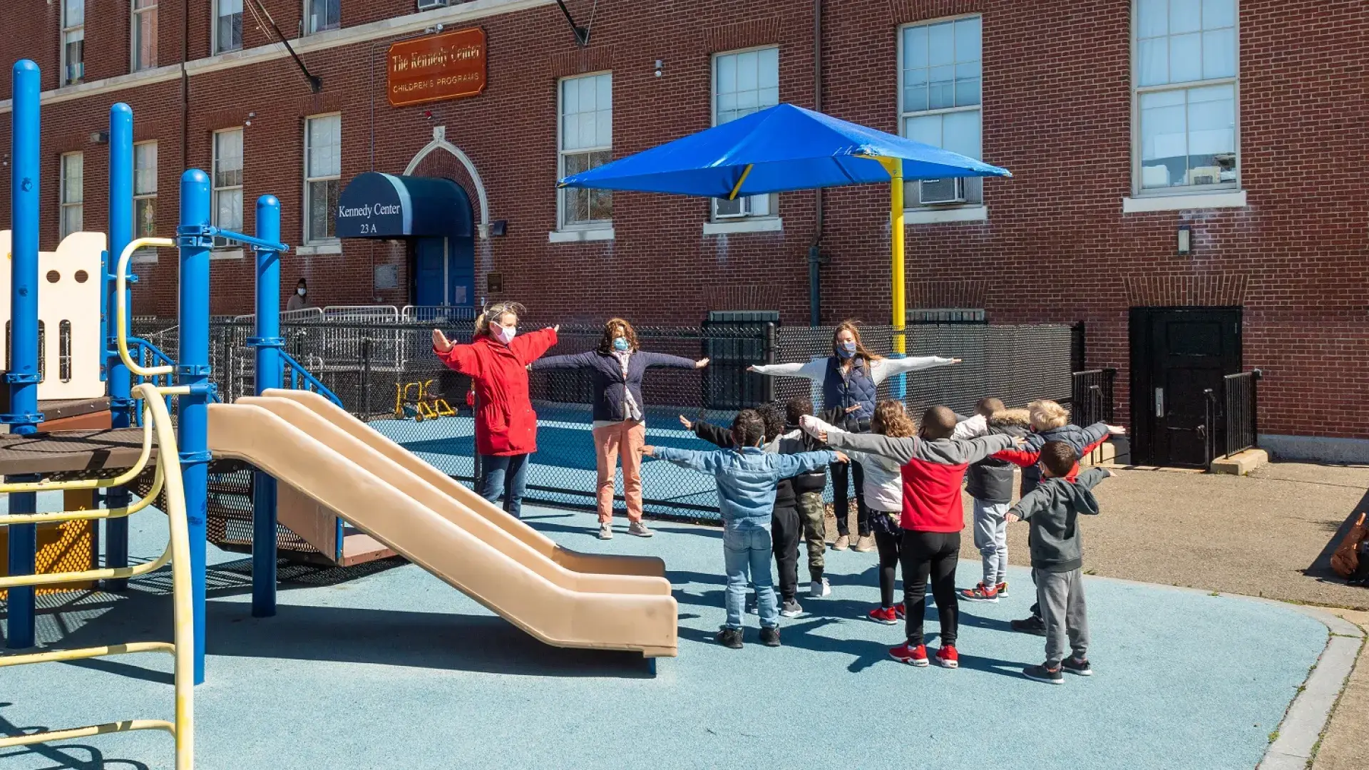 children and adults do exercises in a playground