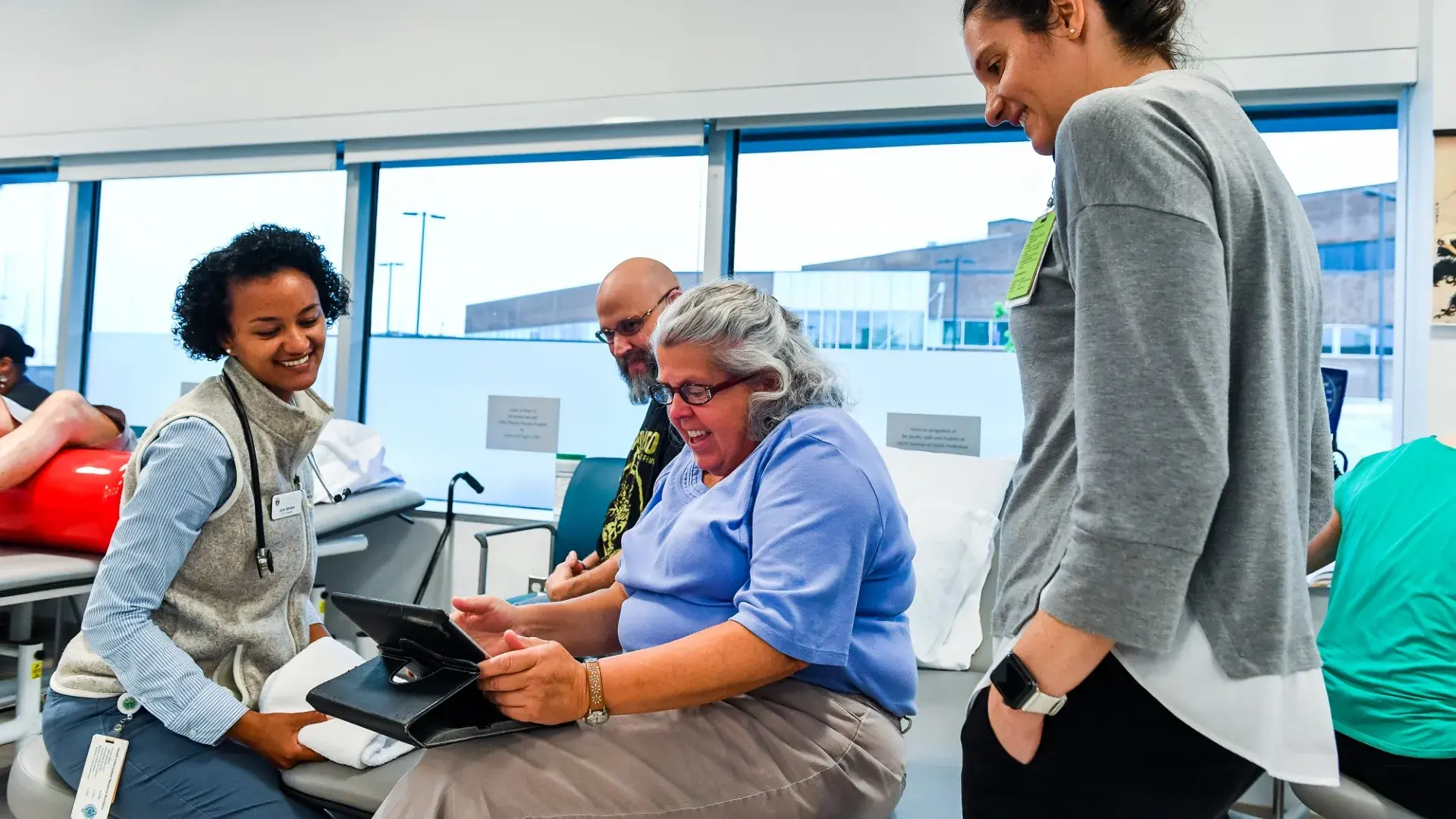 jane, seated, looks at a tablet while students stand around her