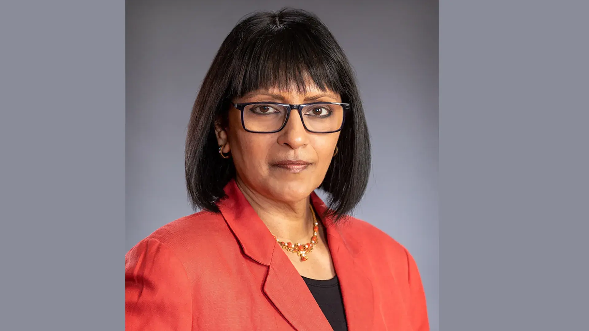 subha wears black rimmed glasses and a red blazer