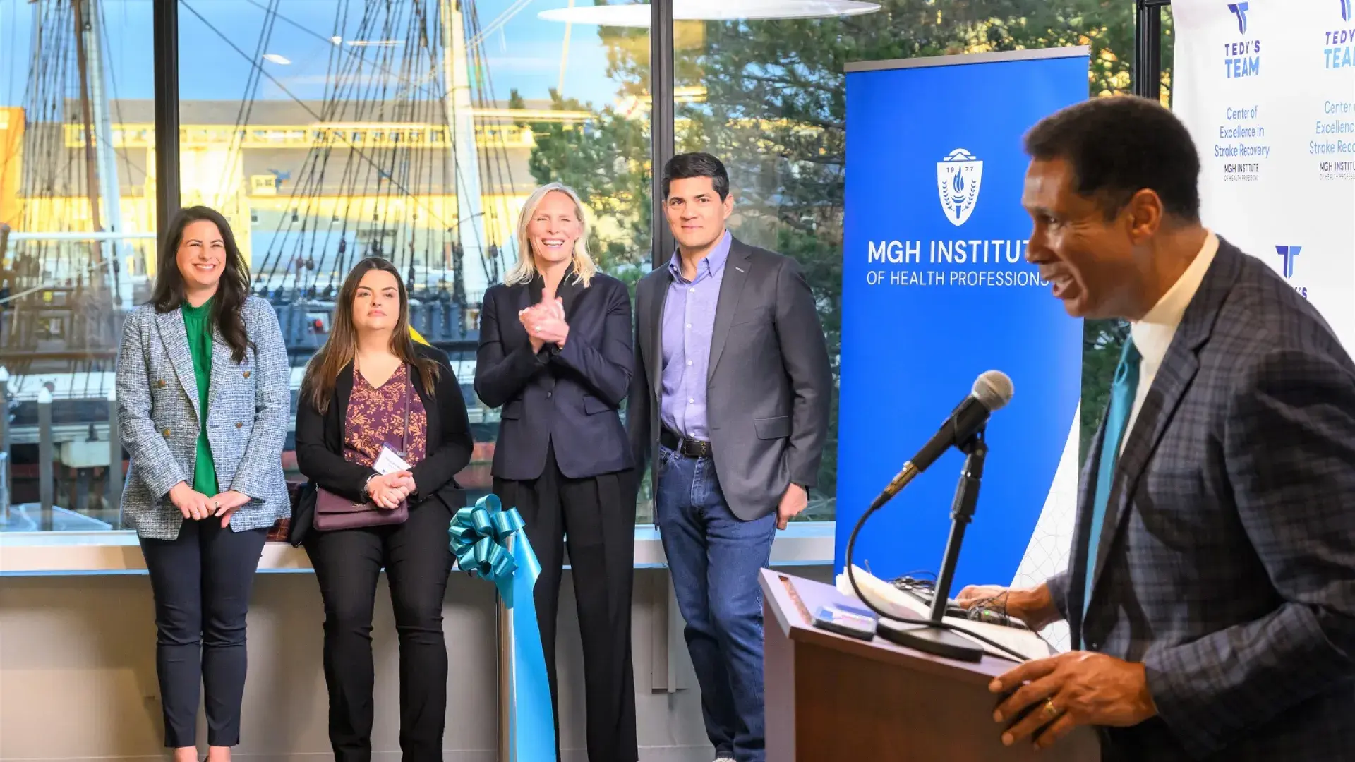 steve speaks at a podium while a group looks on