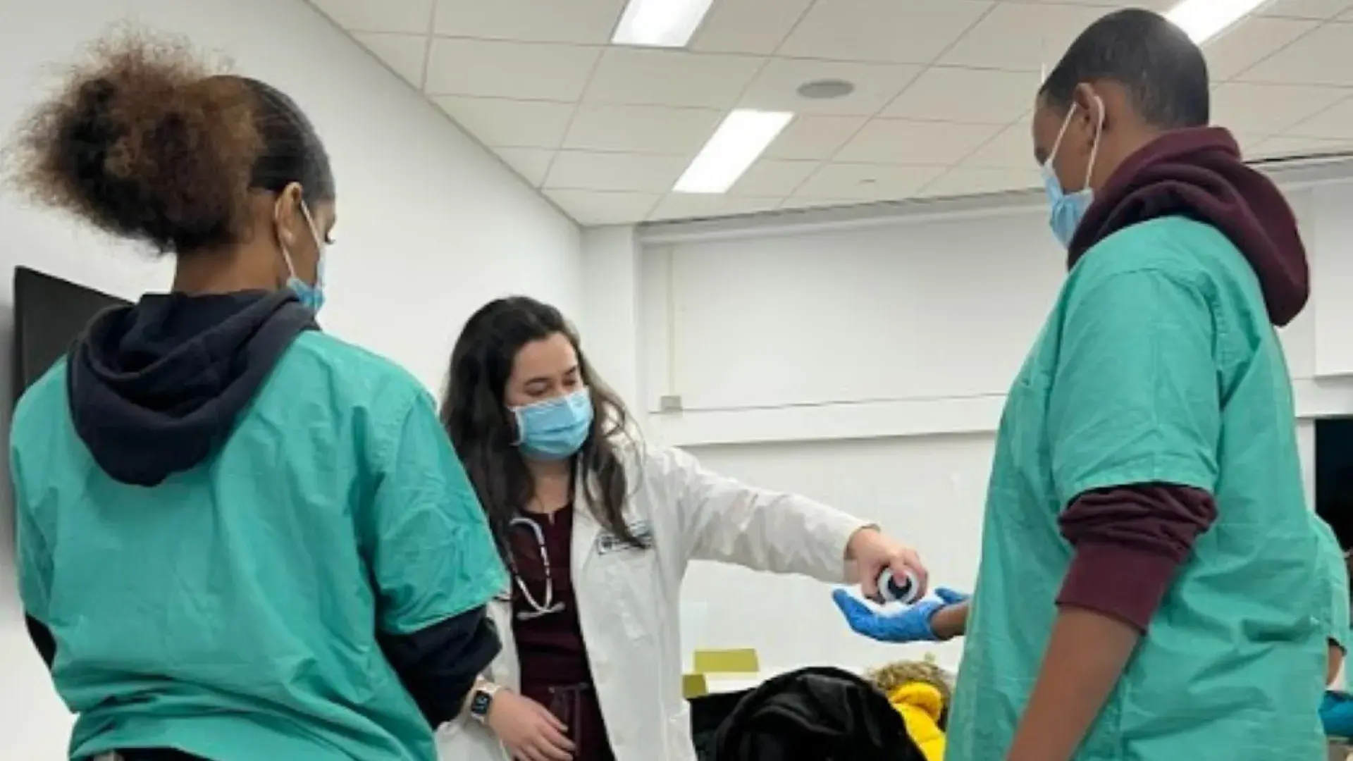 woman squirts cream into the rubber gloved hand of a student