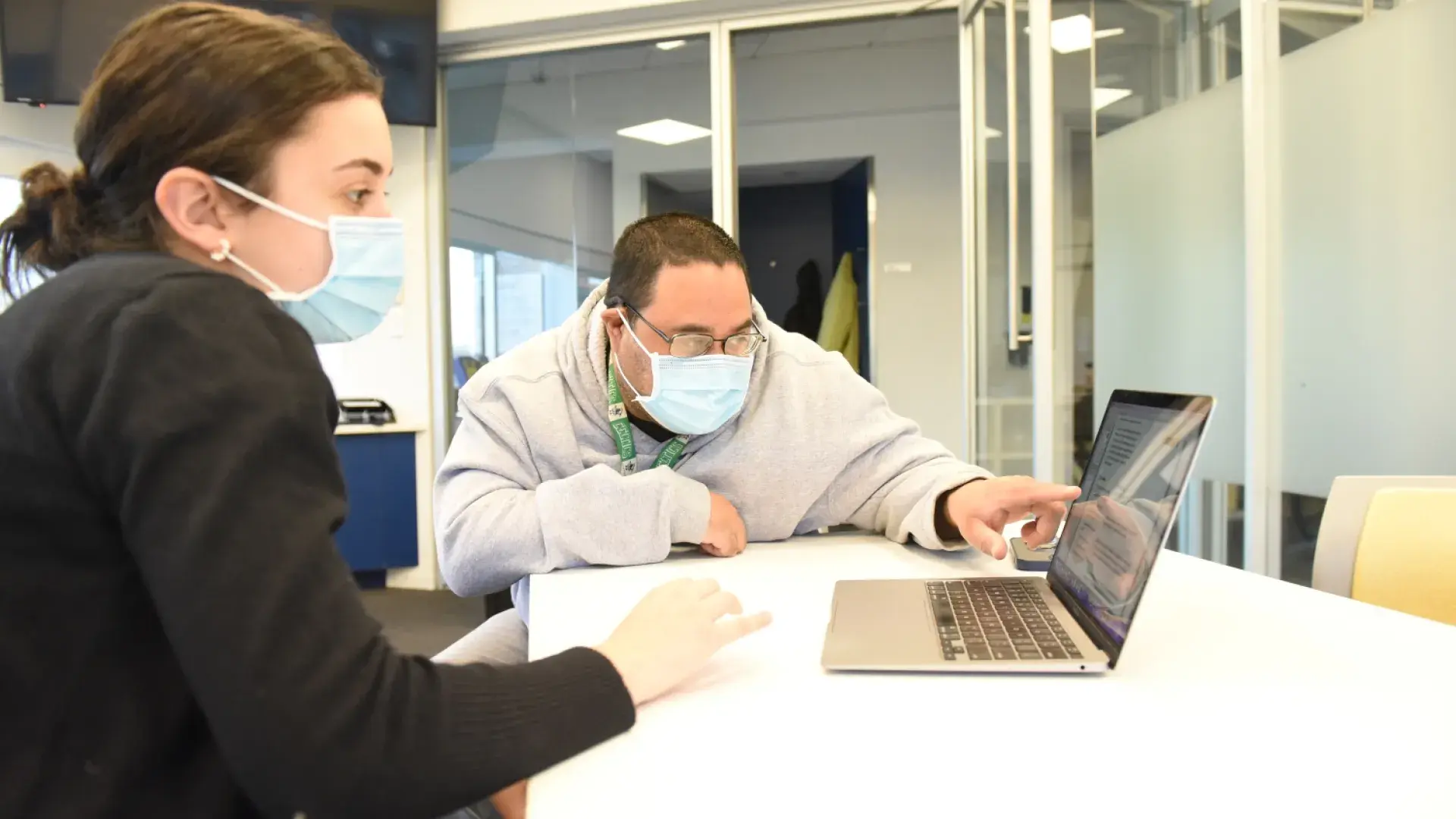 woman looks at laptop while man points
