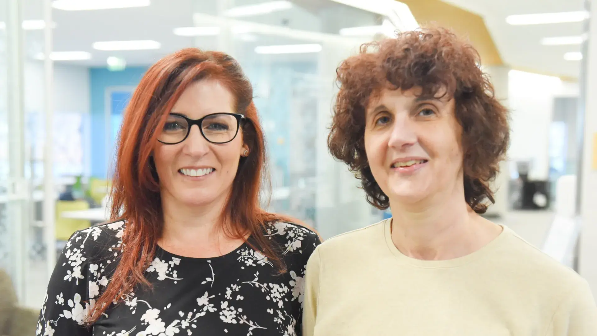 prue has red hair and black rimmed glasses, ann has brown short curly hair and a yellow top