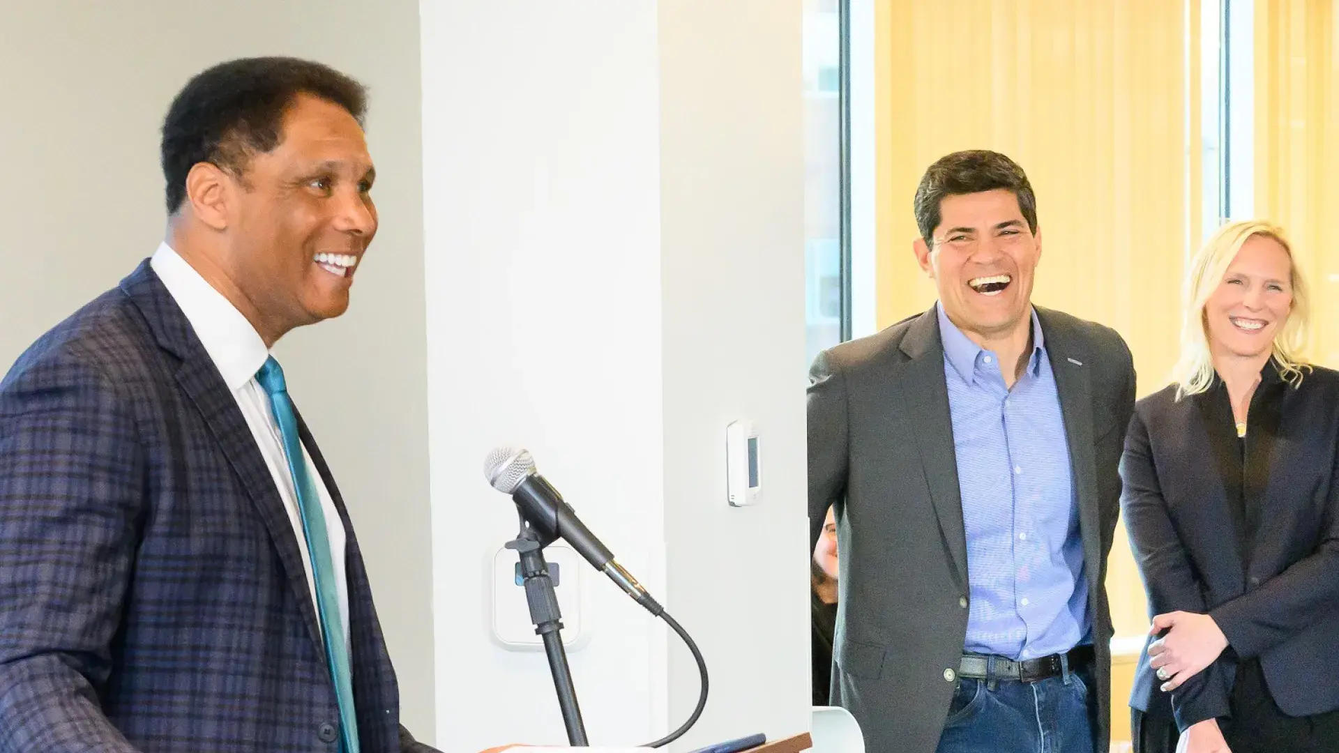 steve stands at a podium and wears a blue plaid suit