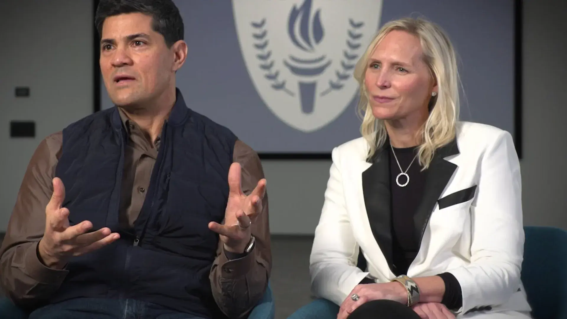 Tedy speaks to the camera and sits in a chair next to heidi 