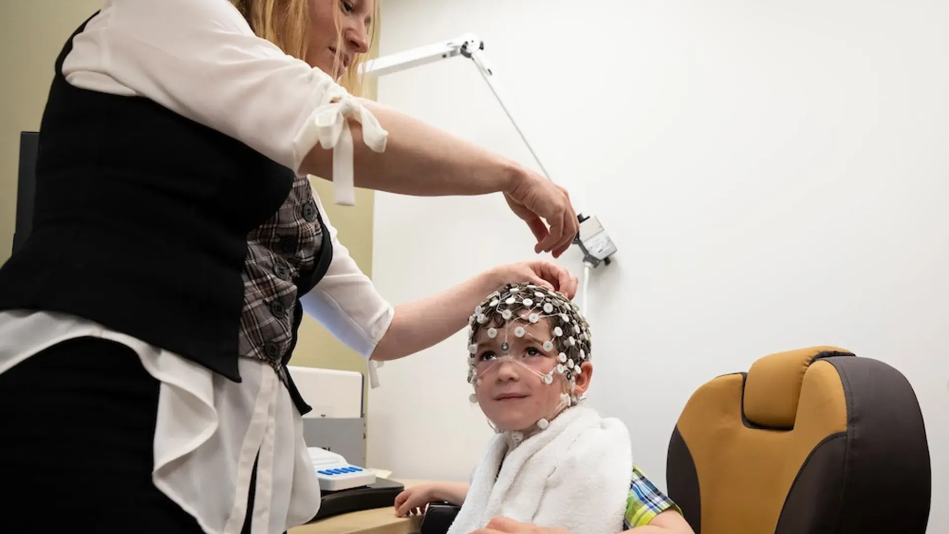 yael places a cap made of tiny white circles on a little boy's head