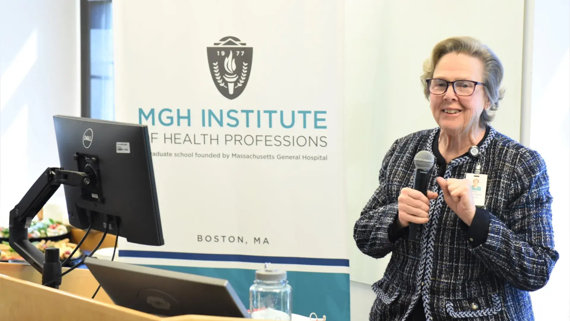 paula smiles and makes a fist pump gesture with a microphone in the other hand