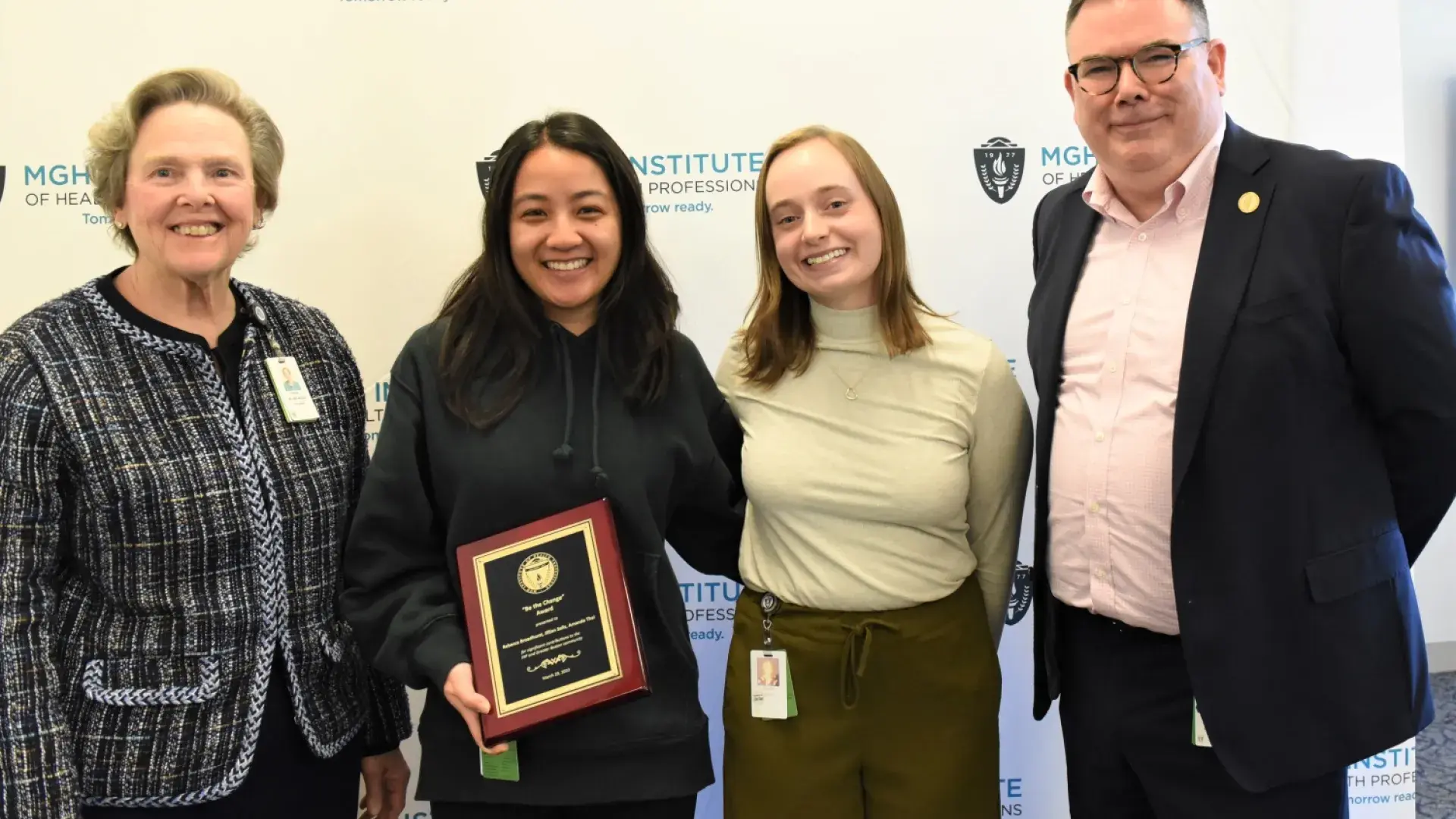 amanda holds a black and gold plaque and has her arm around jillian