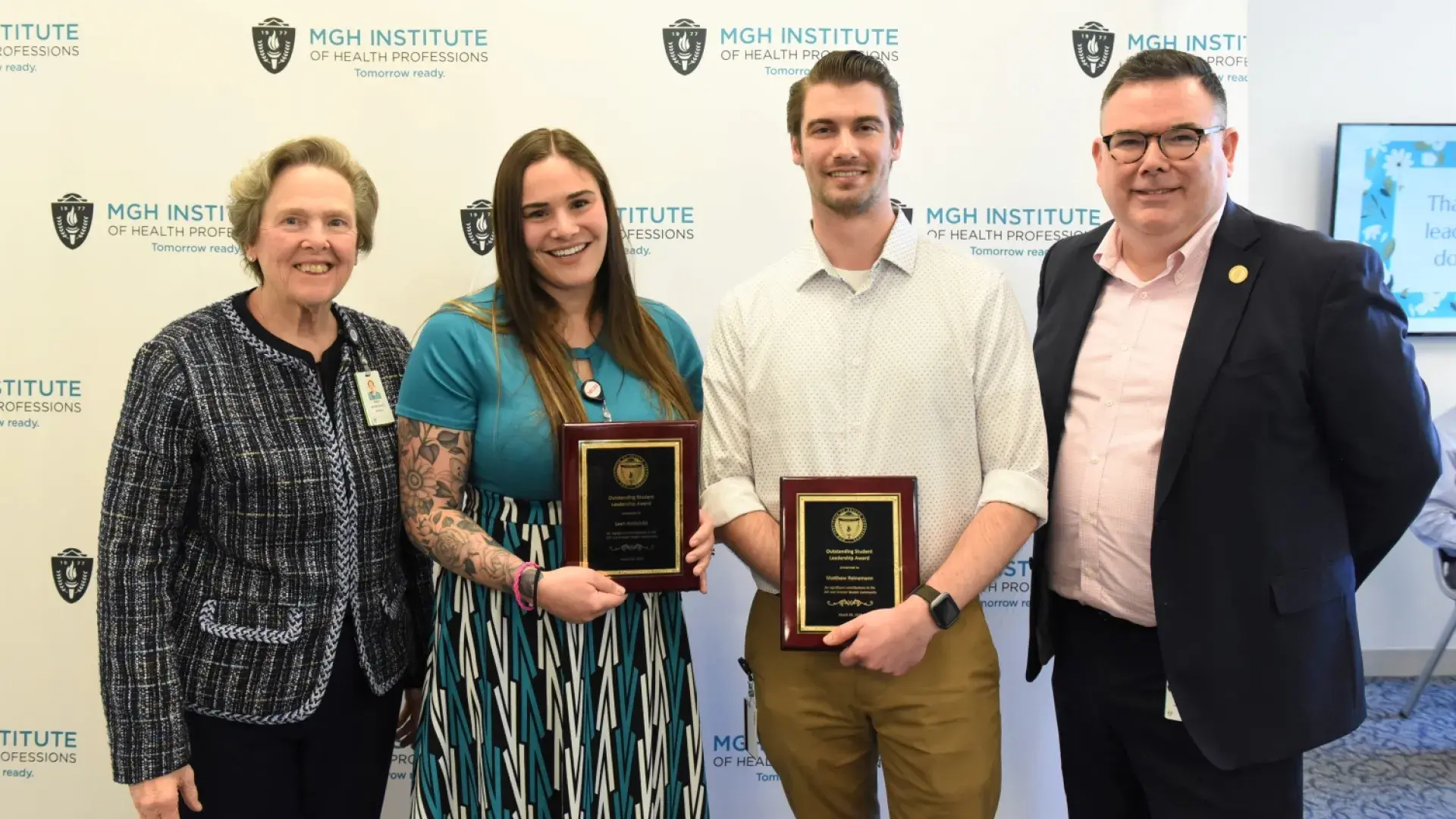 leah and matthew smile and hold matching black, gold and wood plaques 