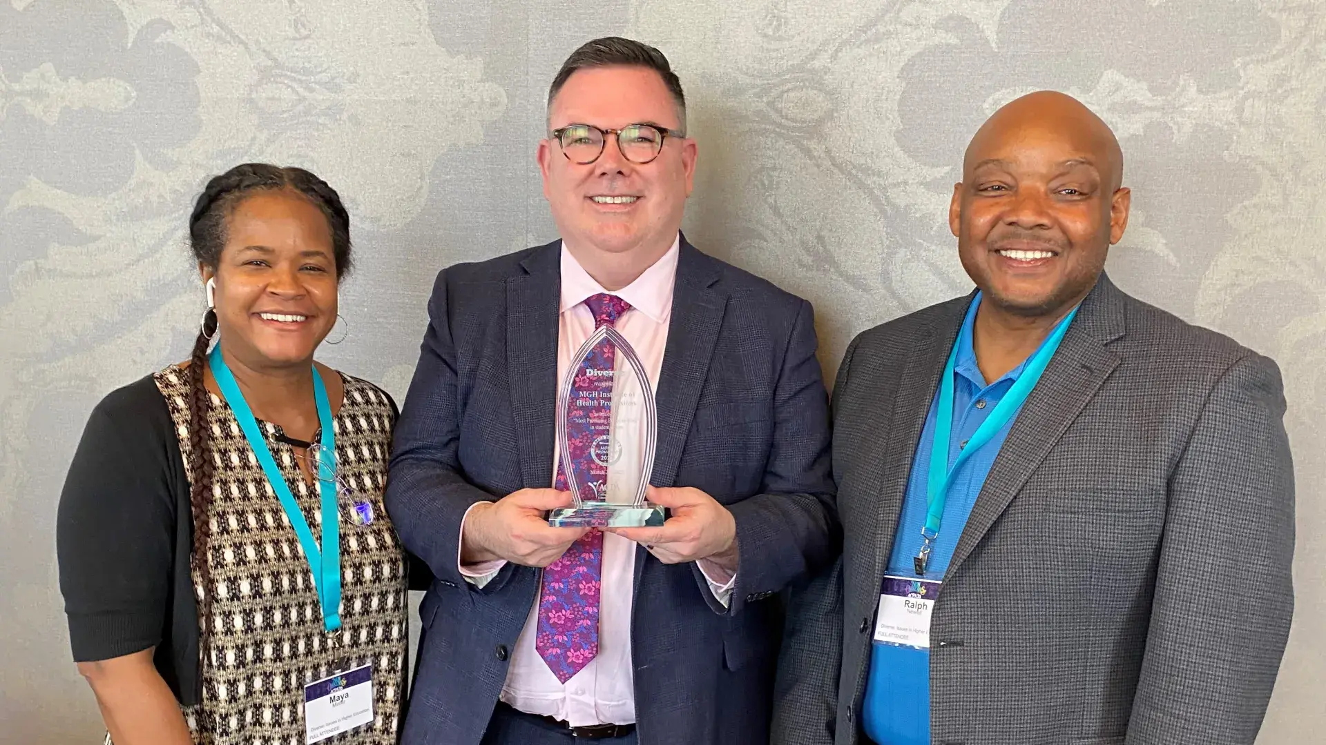 jack wears a purple tie and navy suit and holds a tear drop shaped award 