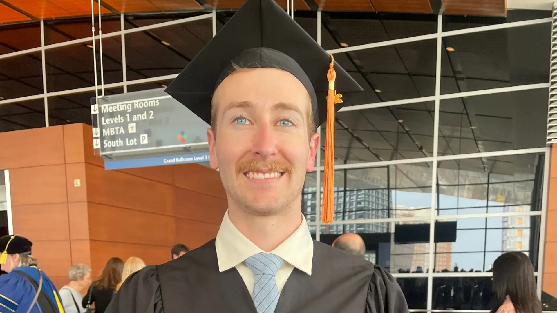 matt has blue eyes and a light brown mustache he wears a black graduation cap and gown