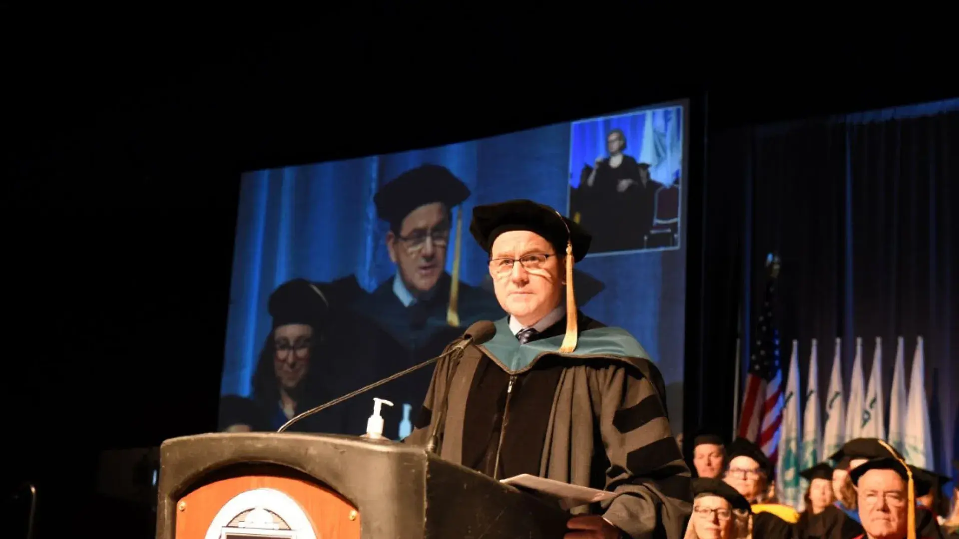 man stands at podium in graduation cap