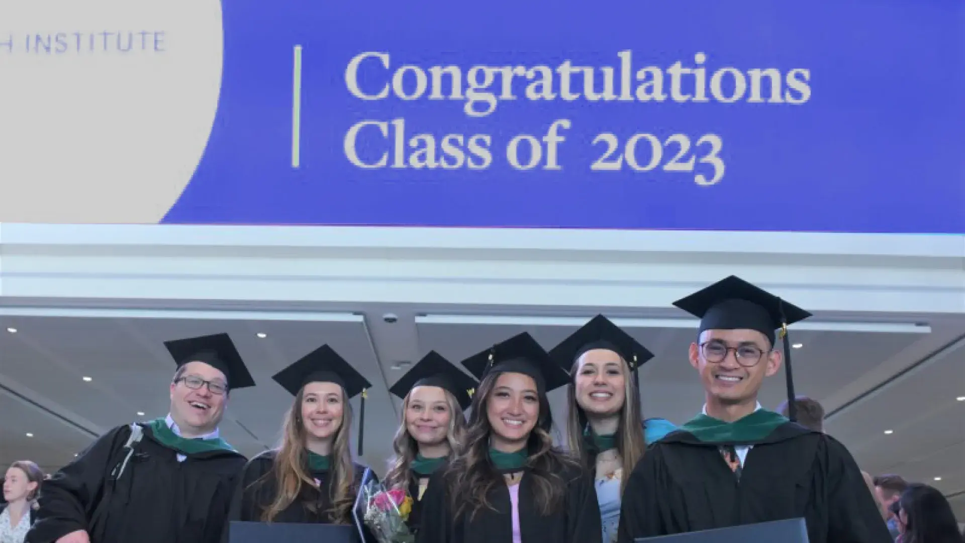 men and women in front of a 2023 sign