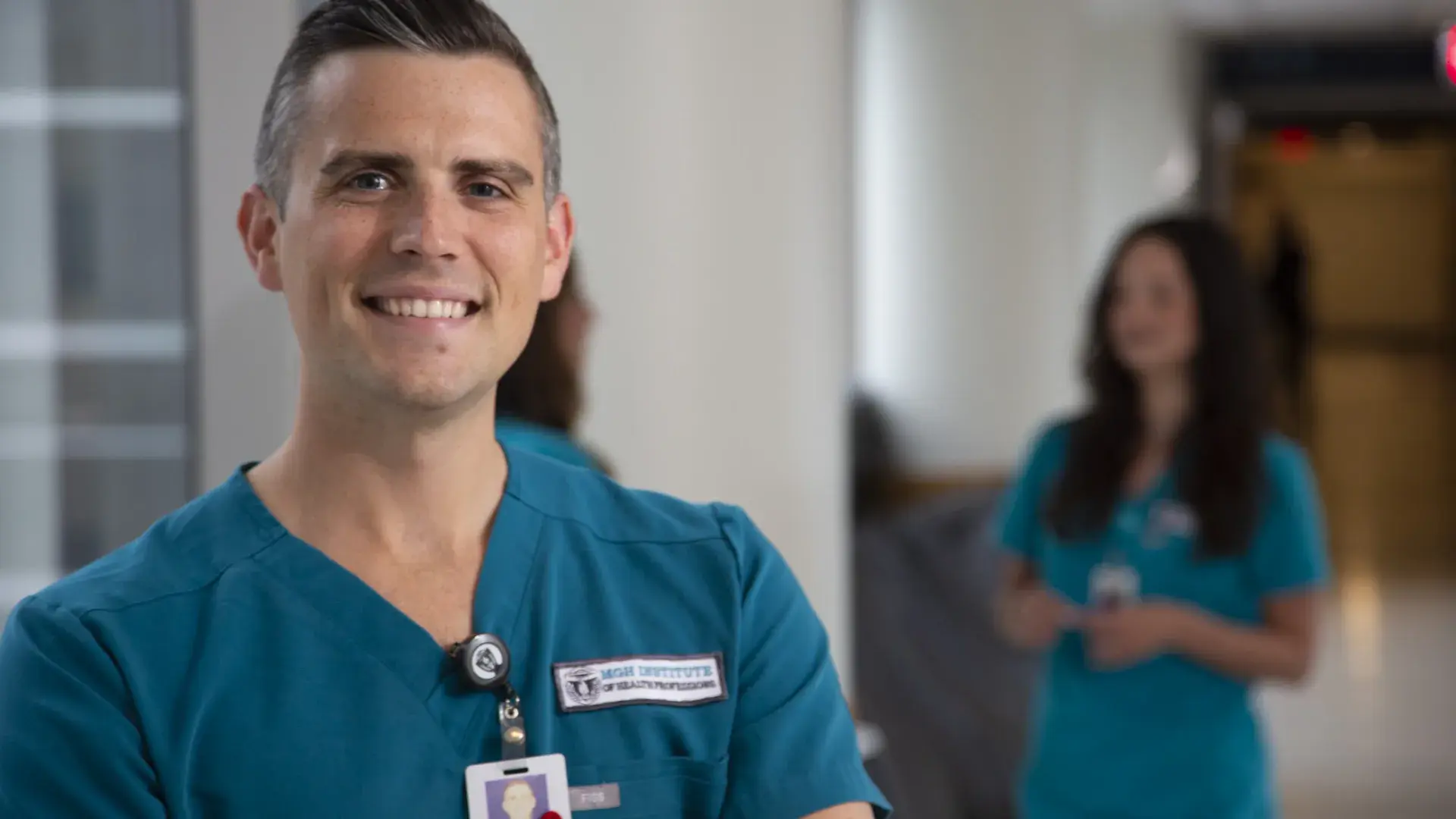 tyler has close cropped dark hair with grey temples and stands in a hospital hallway