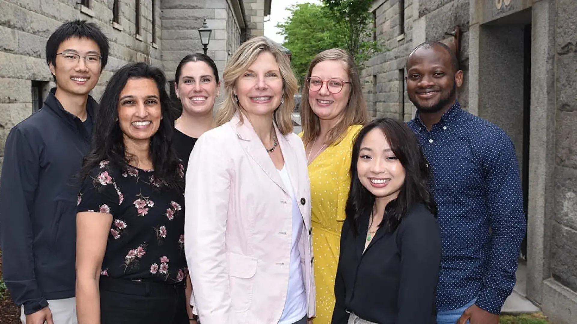 a colorful group of people stand next to a brick wall