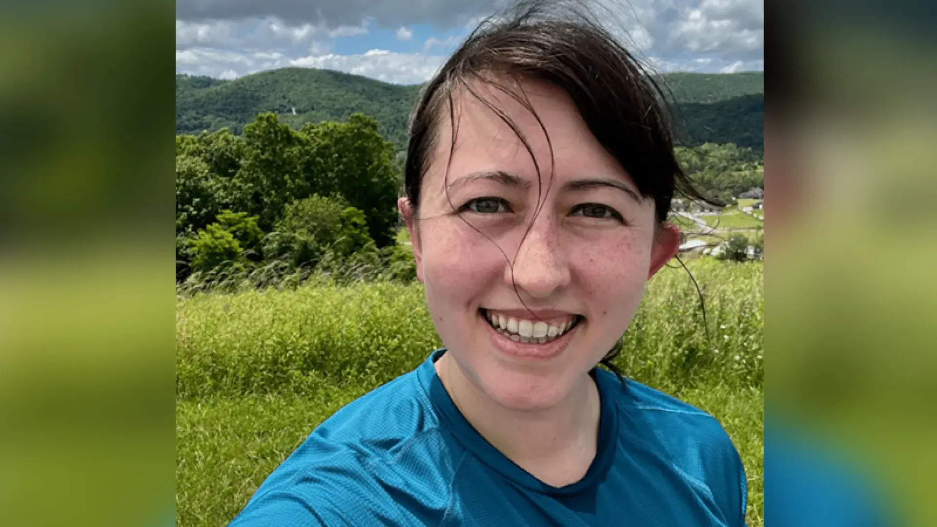 laura smiles in front of green hills