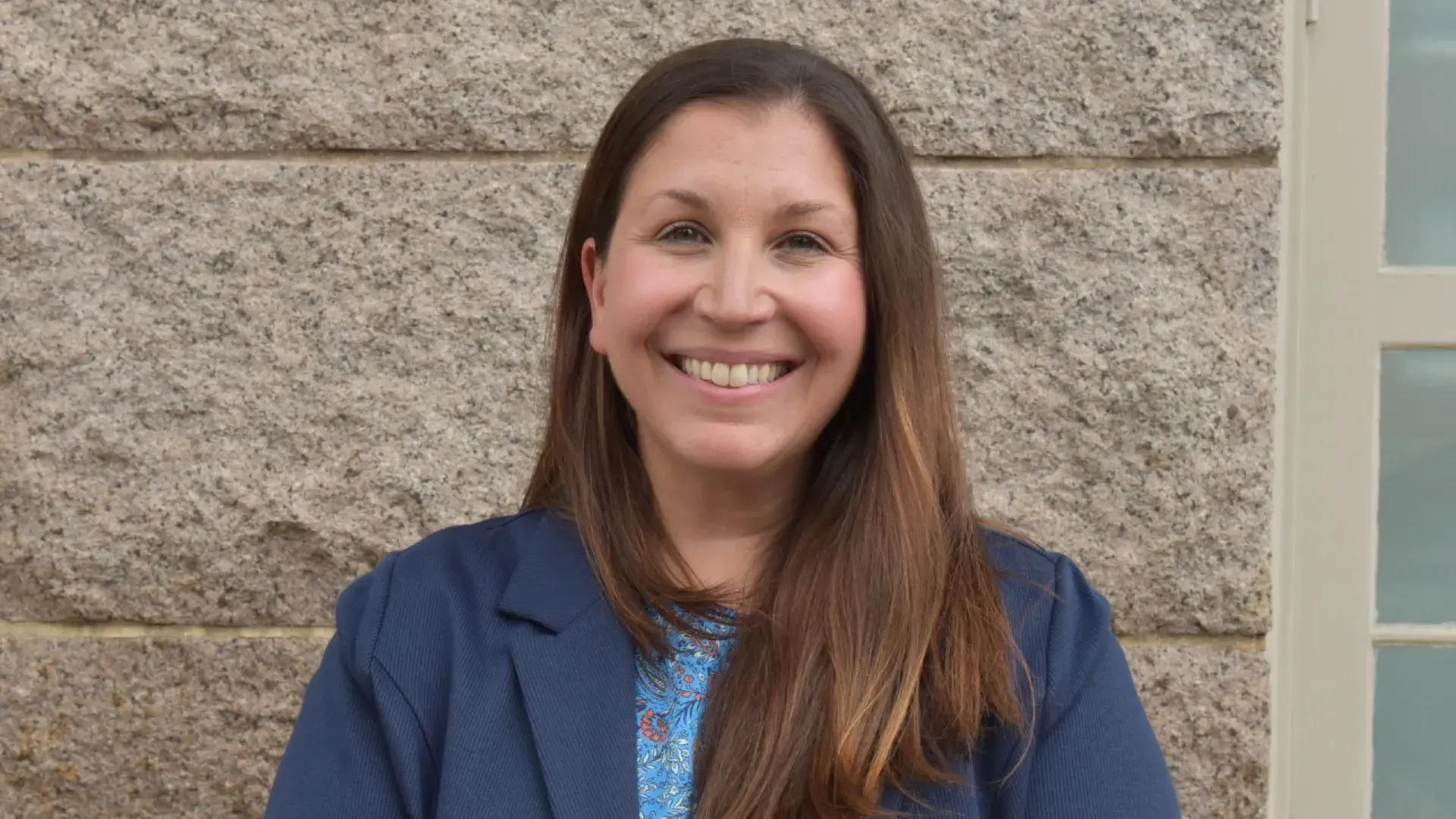 Rebecca Hill stands against a brown brick wall