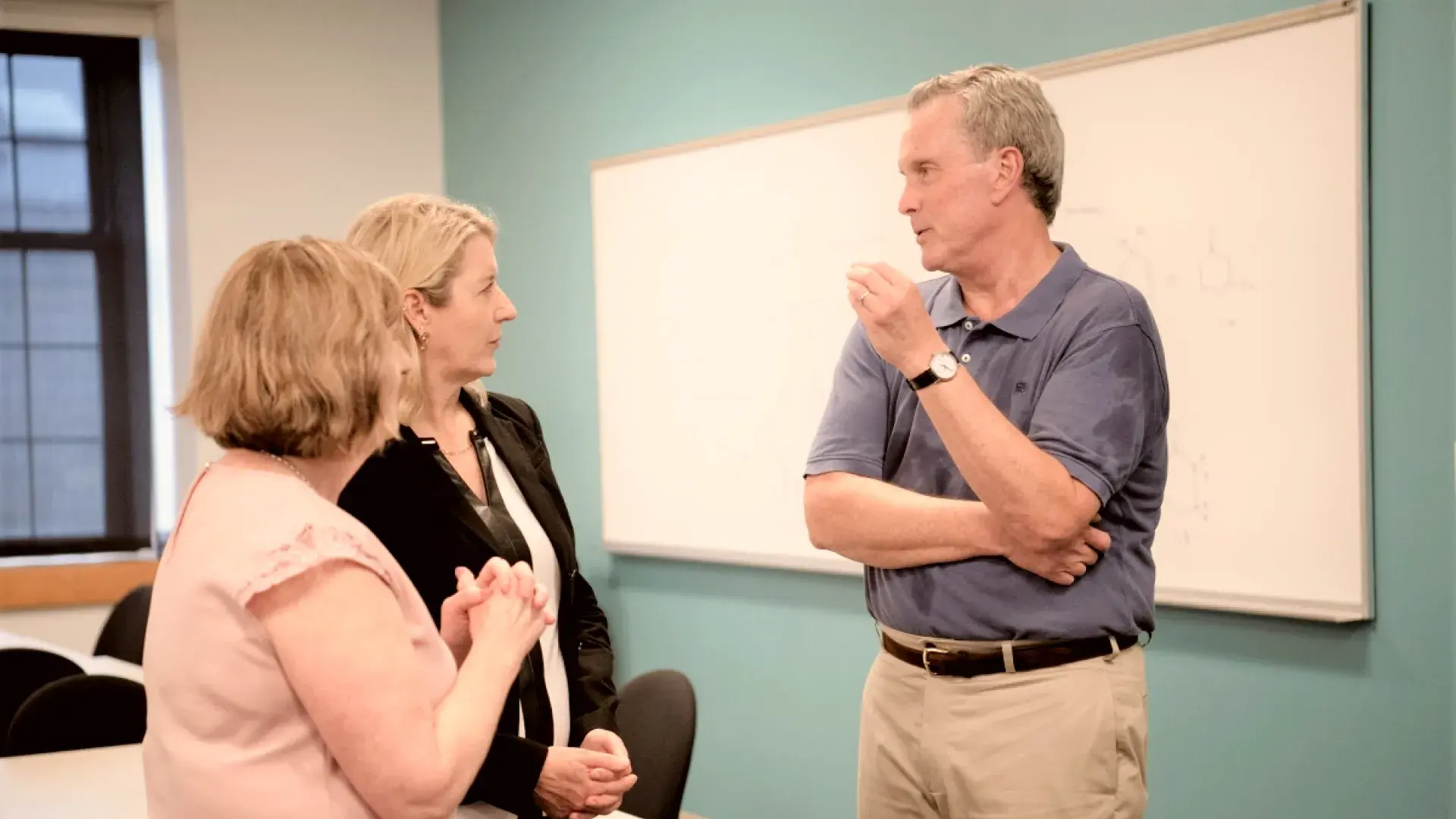 Two women talking to a man in a room