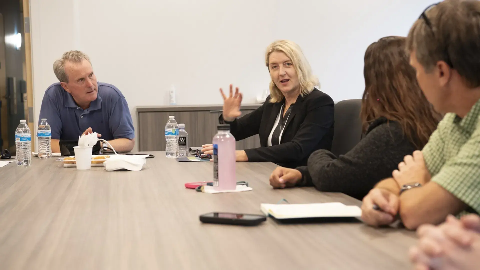 Woman talking to people around a table in a conference room.