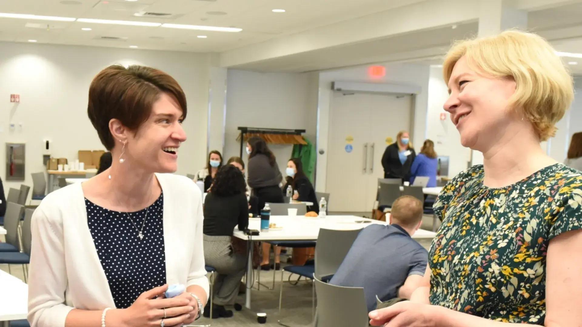 Two women share a laugh in a room.