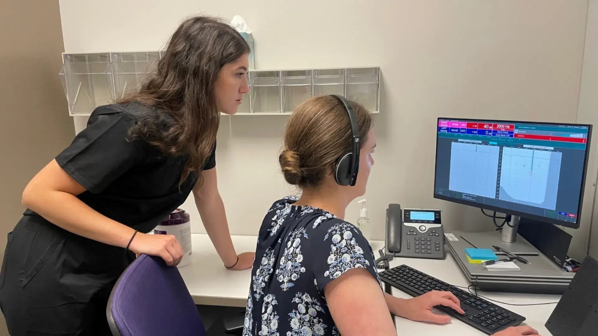 Woman looking over another women's shoulder at computer screen.