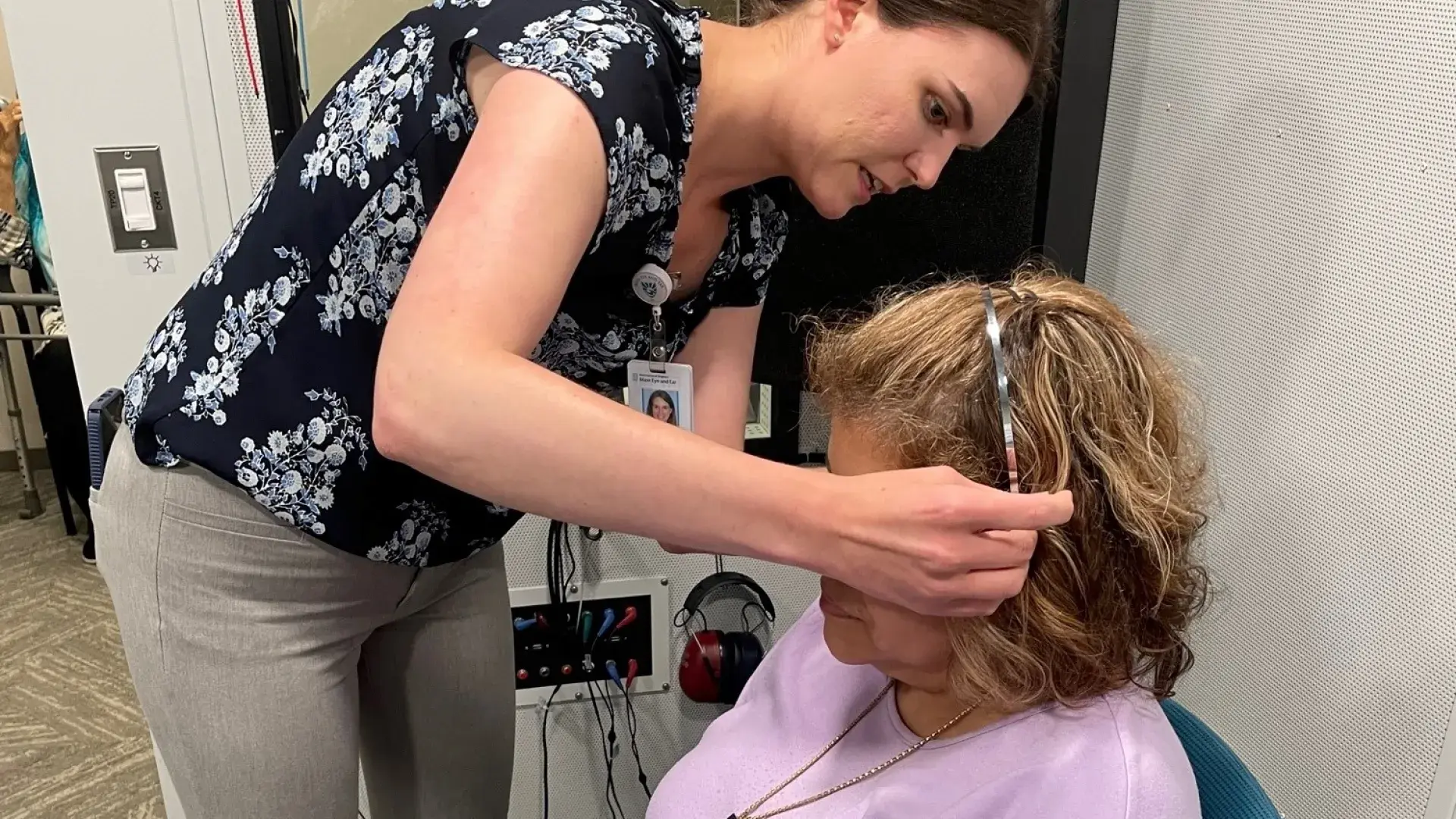 Woman placing headphones on a woman sitting down