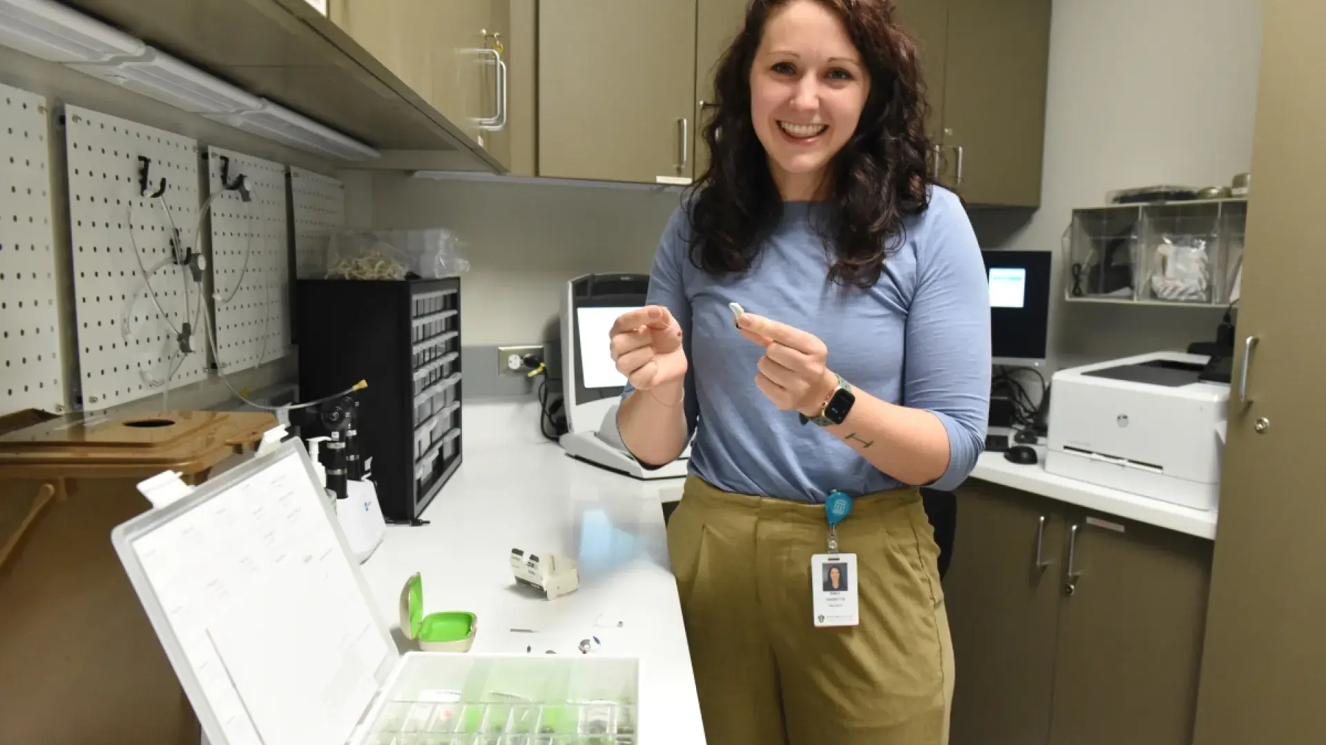 Woman holds hearing aids in a room