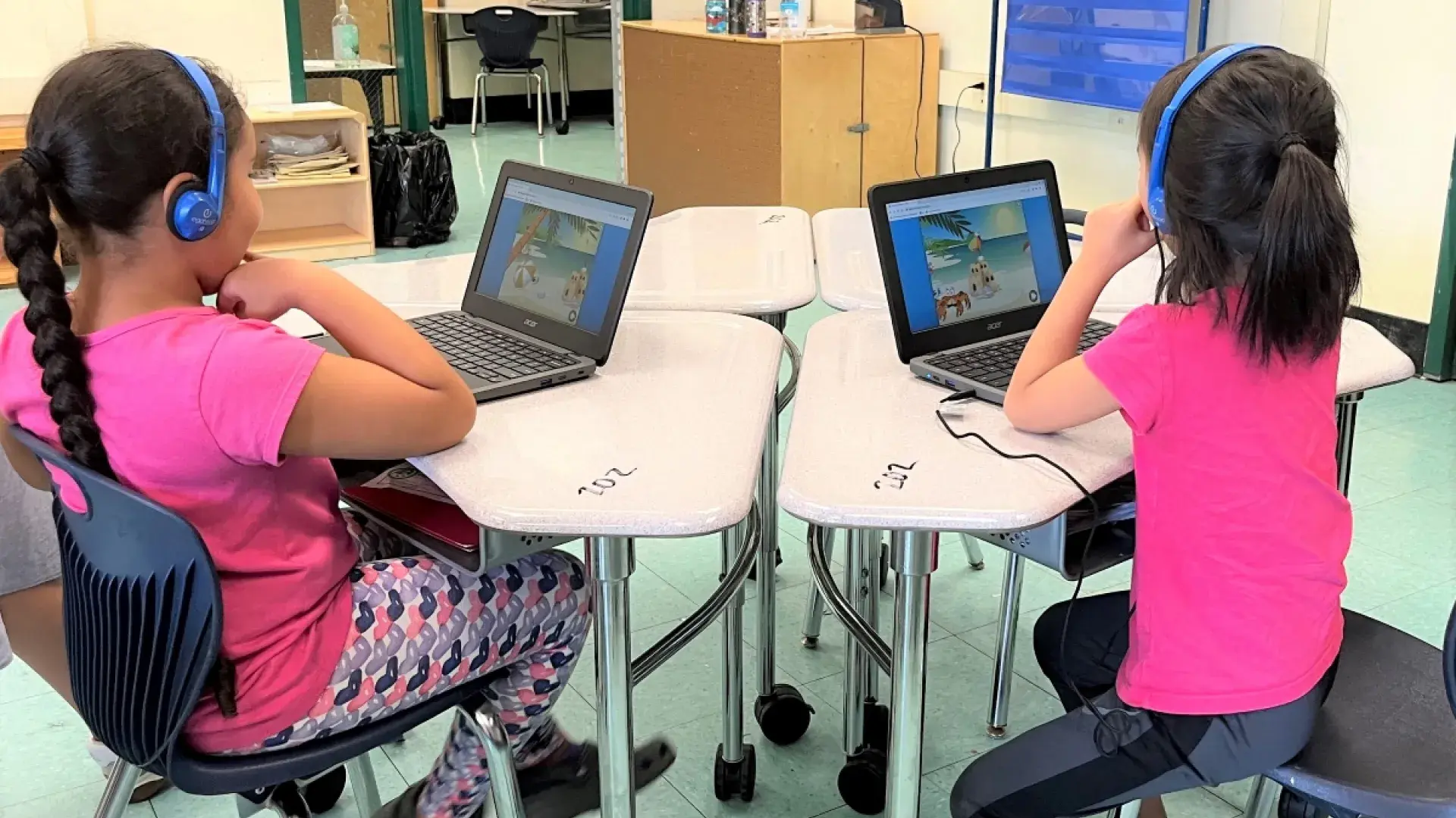elementary kids sitting at desk looking at computers