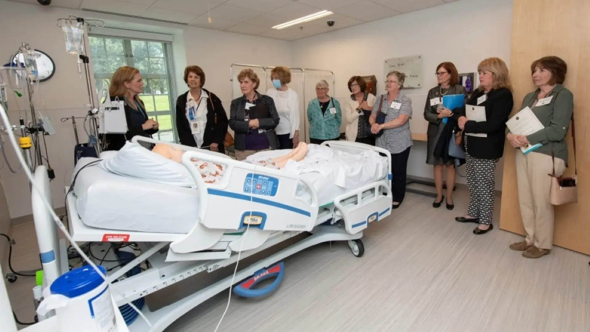 People looking at a manikin in a hospital bed