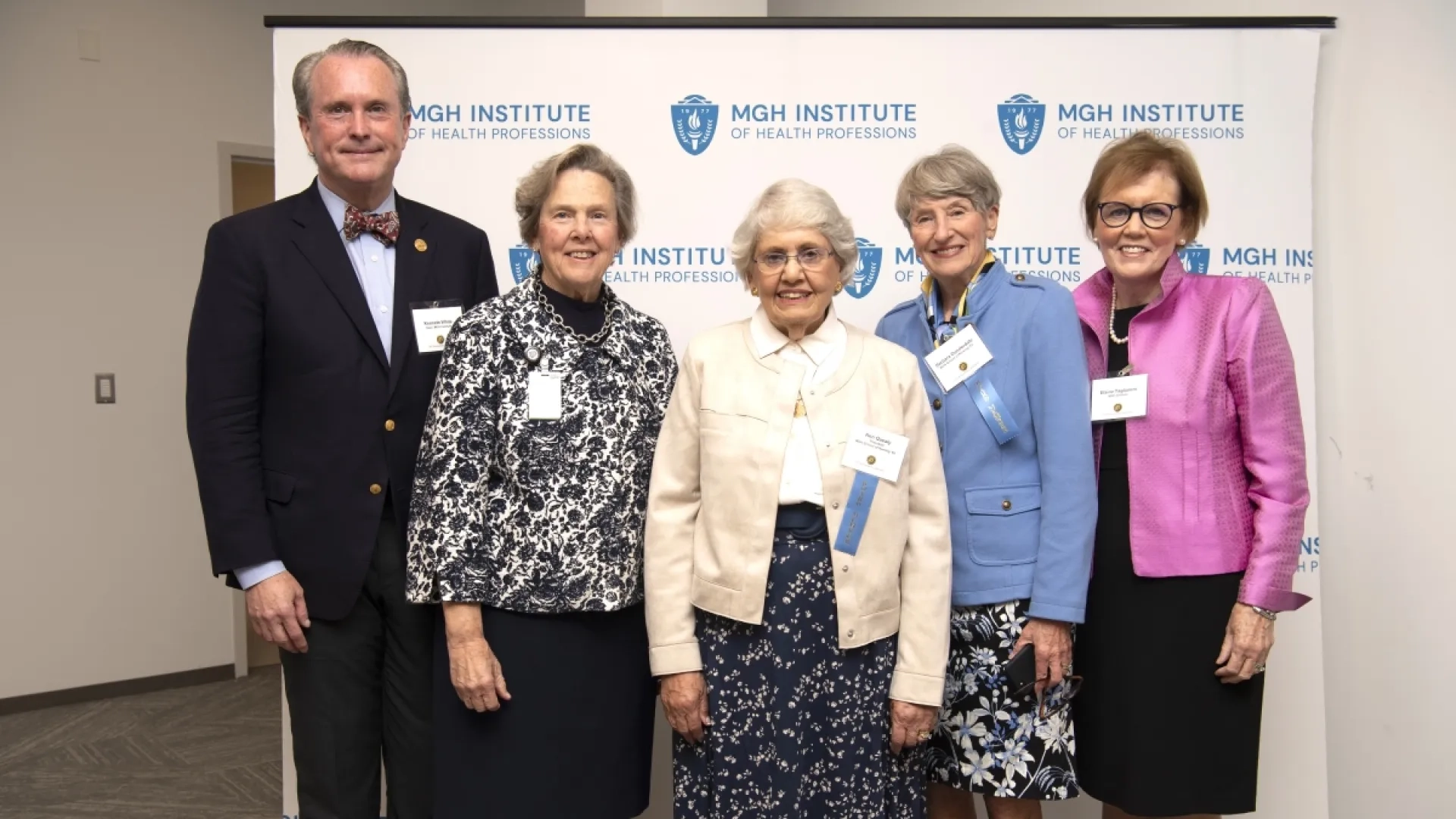 Five people smiling and standing in front of a banner