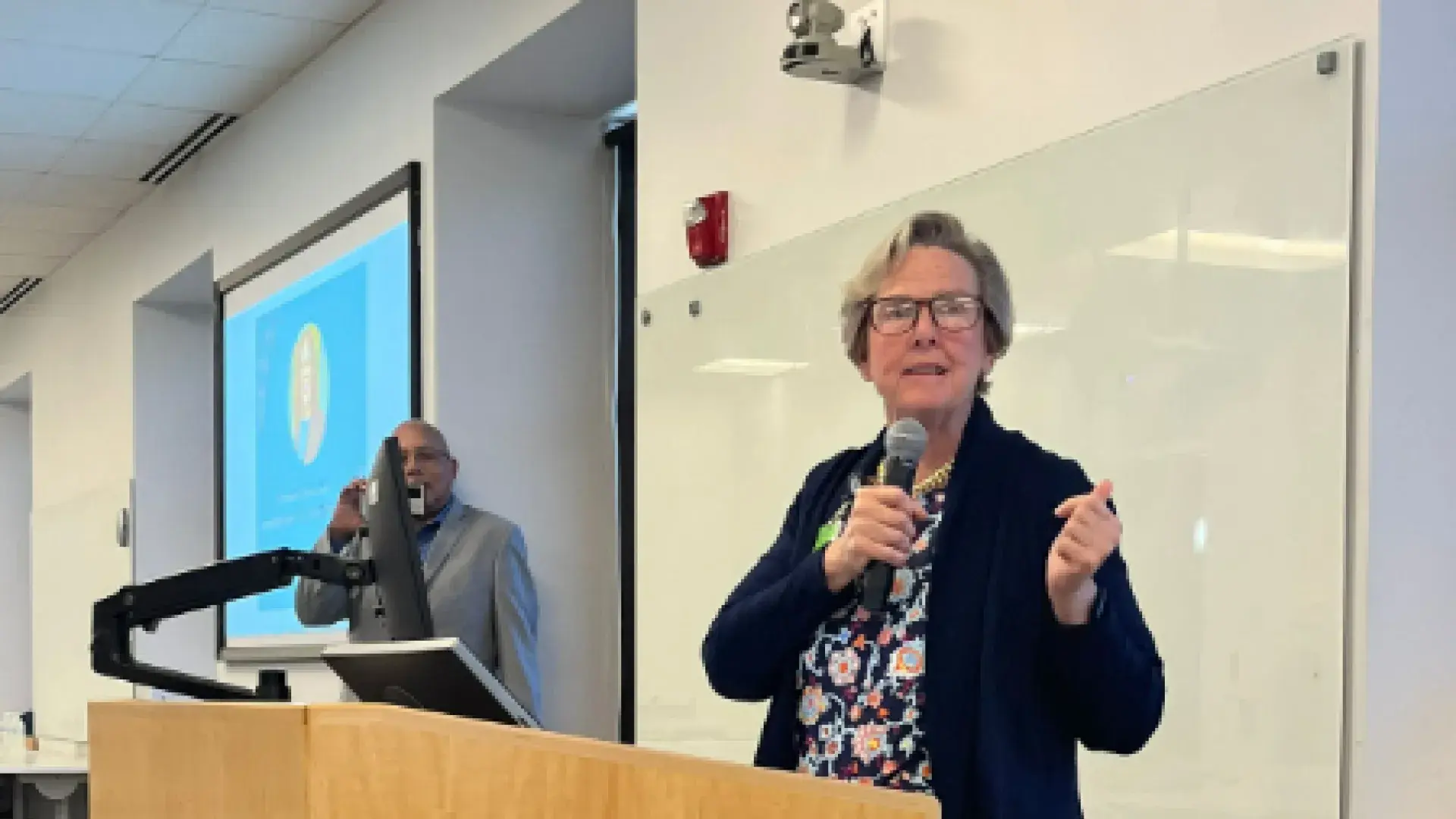 Woman stands at podium with microphone