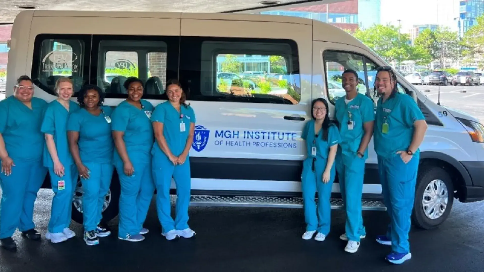 8 people in blue scrubs stand in front of a white van