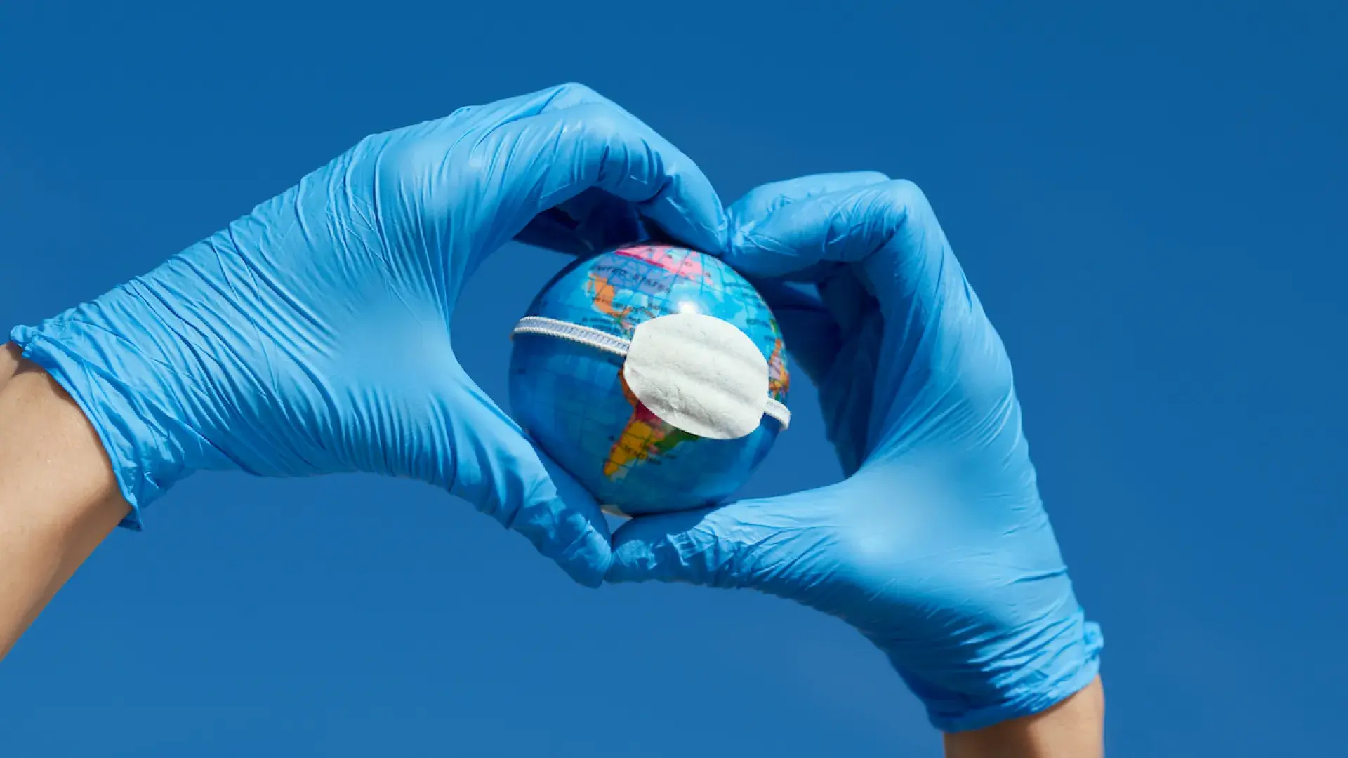 blue surgical gloved hands with masked model of the earth