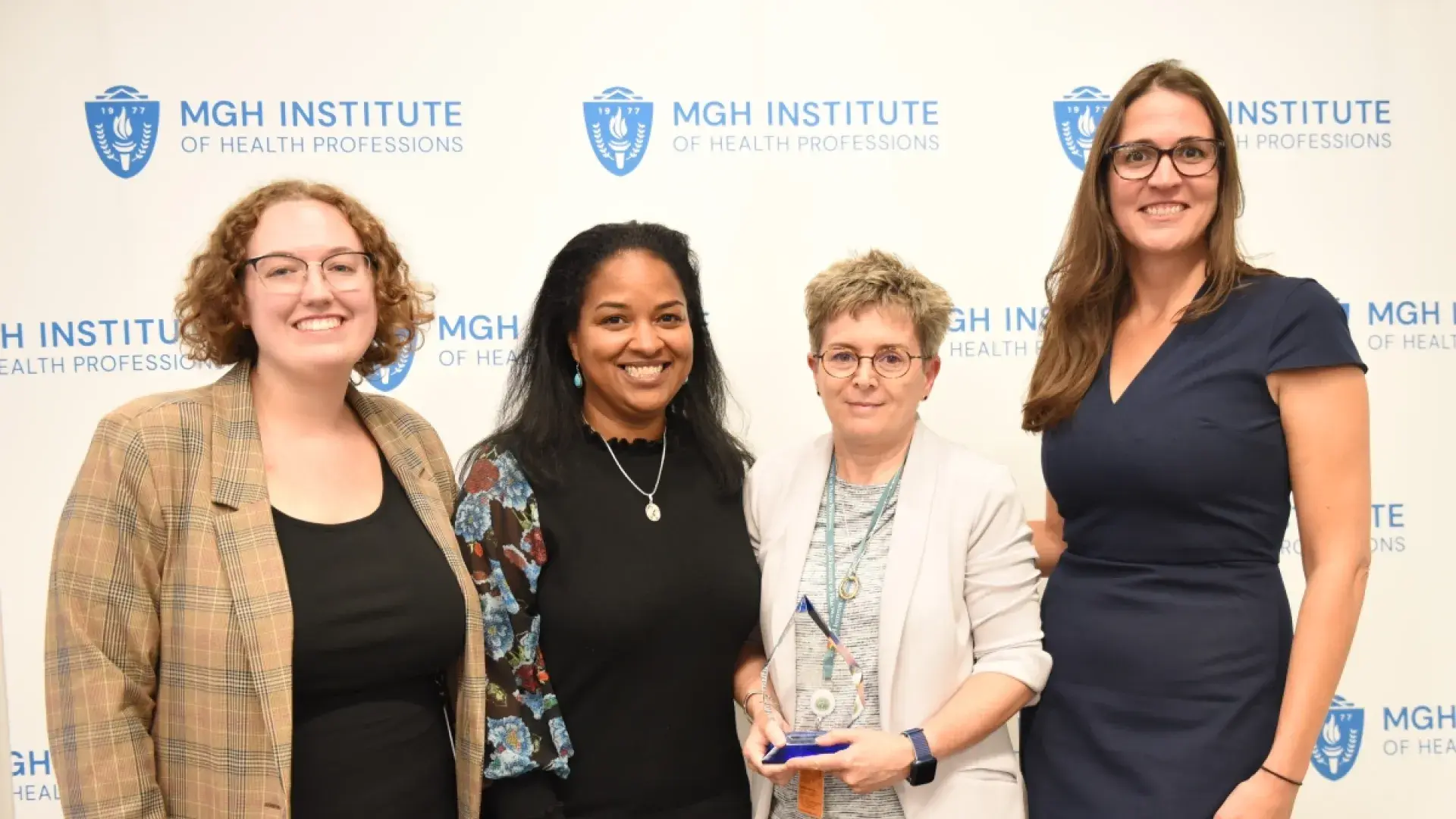 Four people smiling in front of a banner