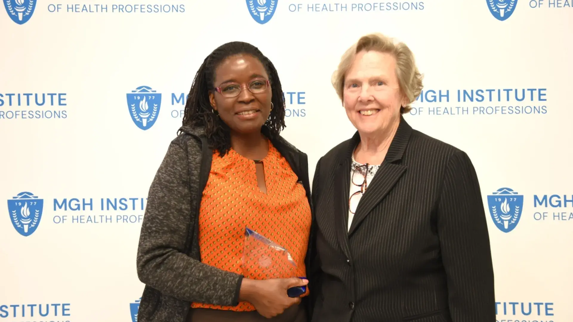Two women smiling in front of a banner
