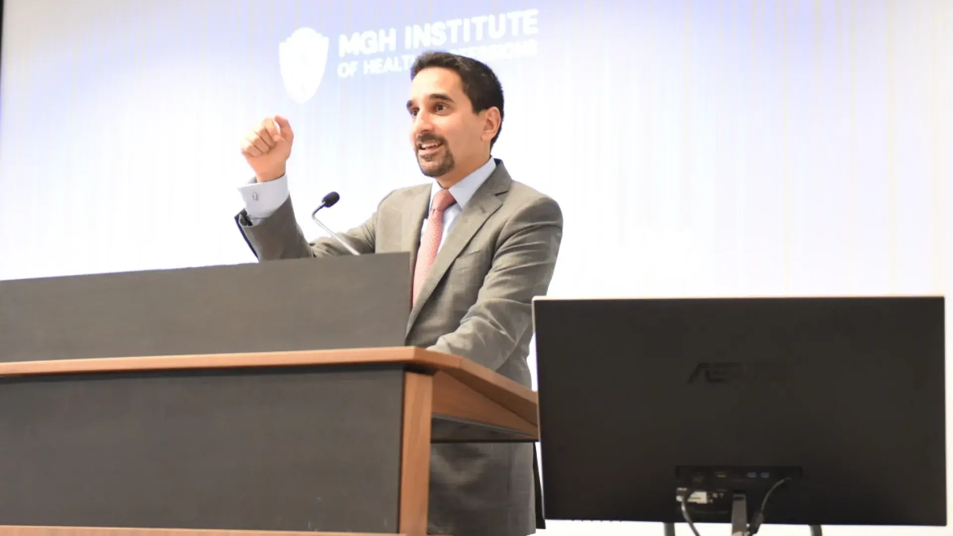 Man with goatee gestures while speaking at a podium