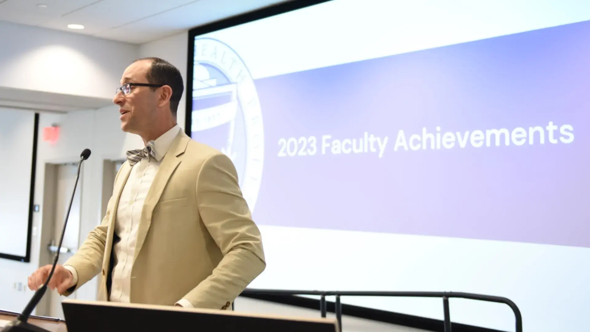 Man with glasses speaks from podium