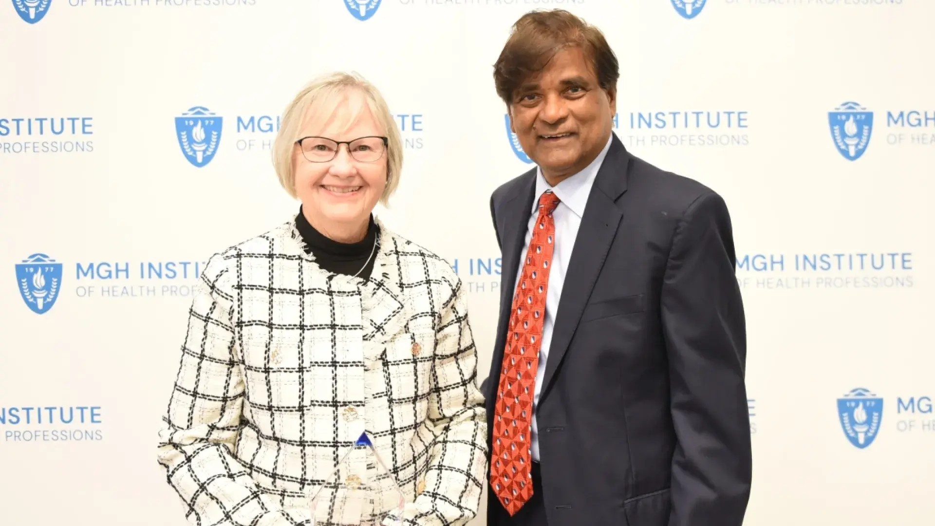 Woman and man smiling in front of a banner