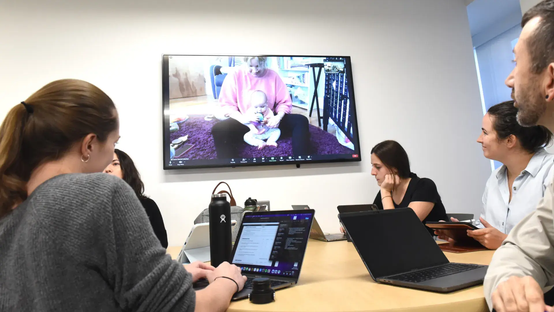 People sitting around a table watching a wall monitor
