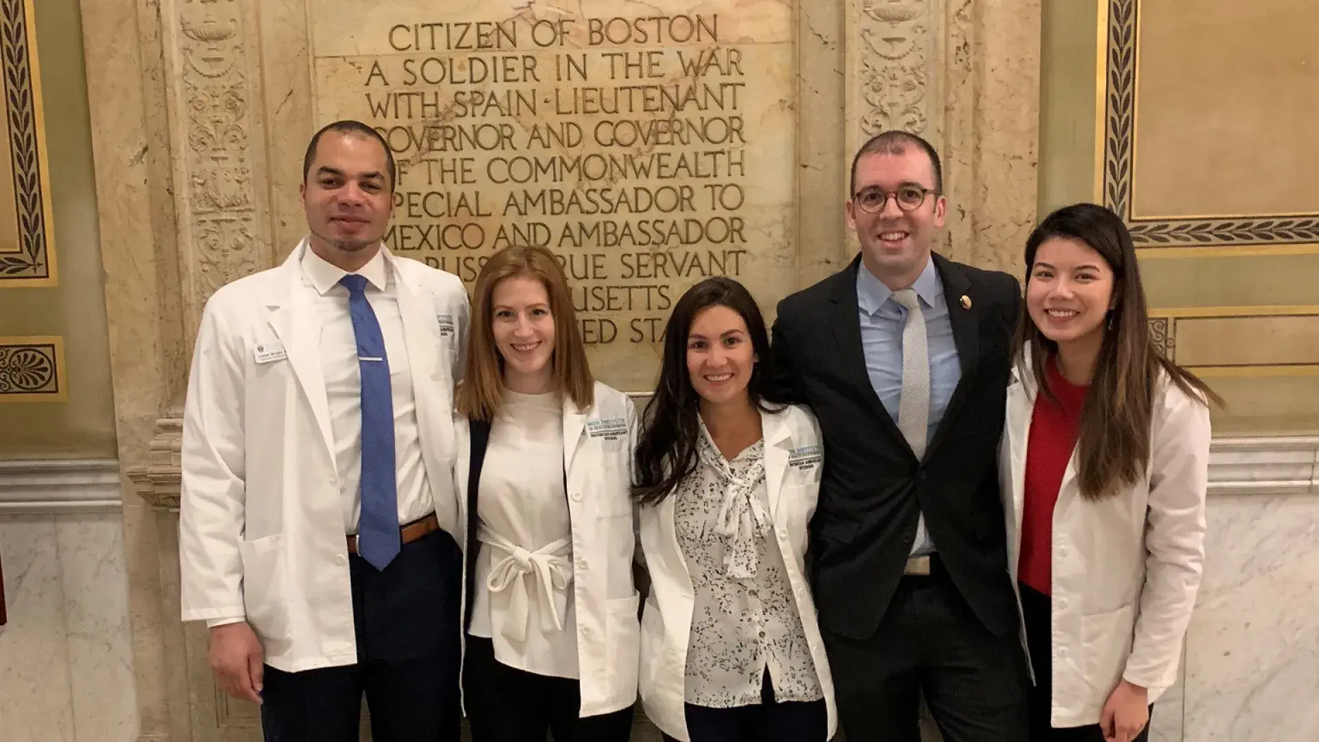 two men stand with three woman at state house