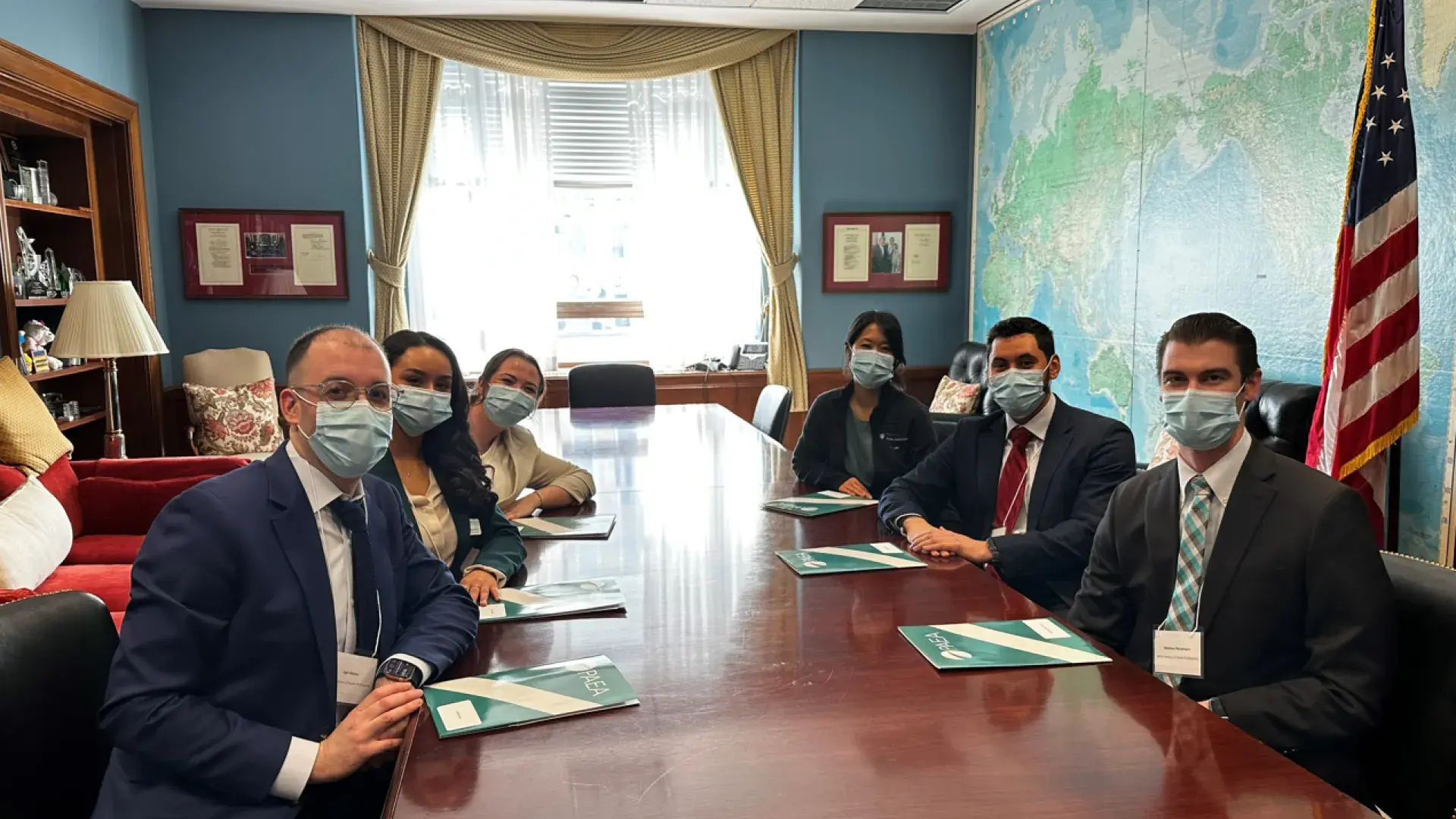 man sits with students in masks inside political office