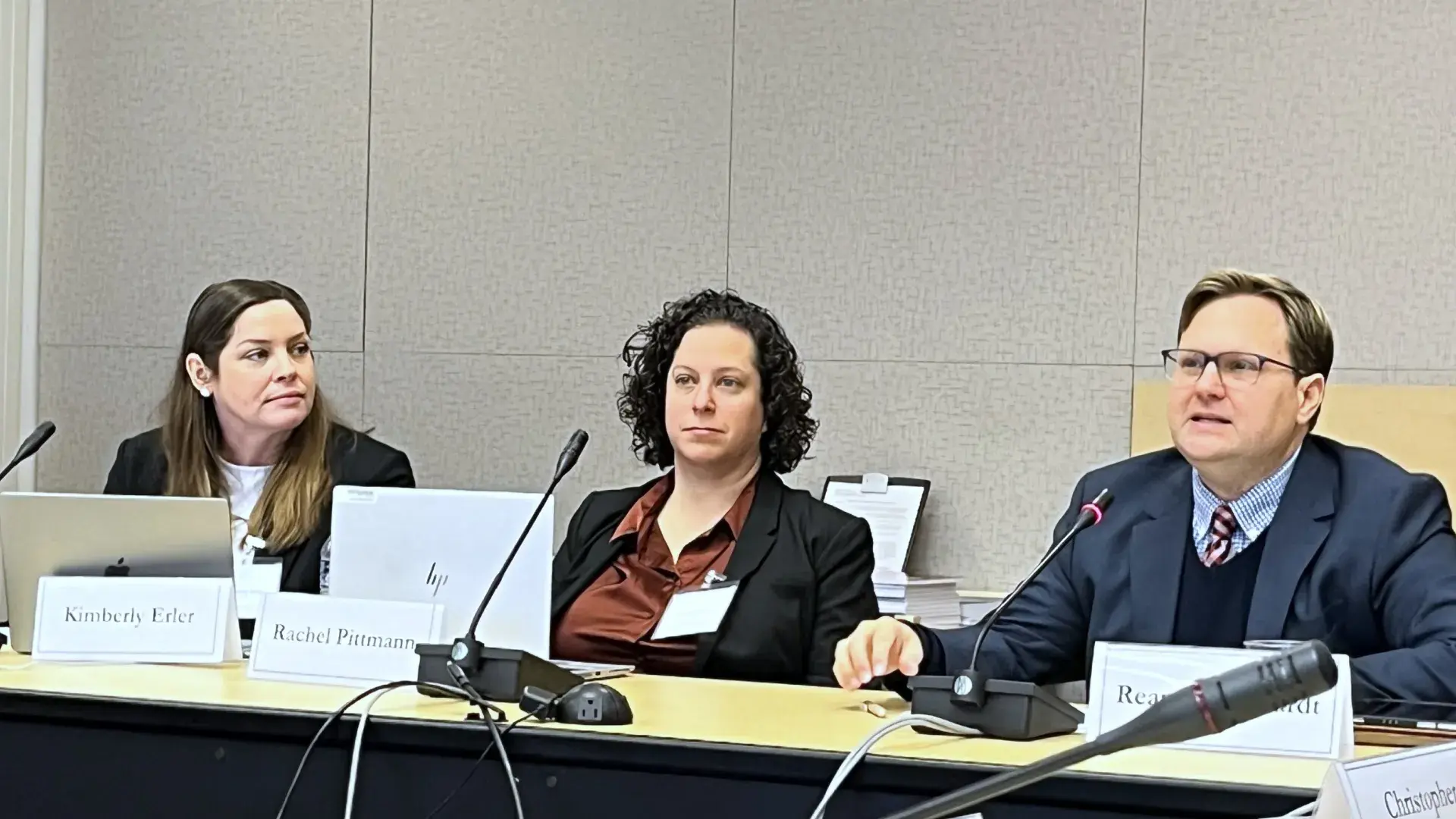 Three people testifying while sitting at a table