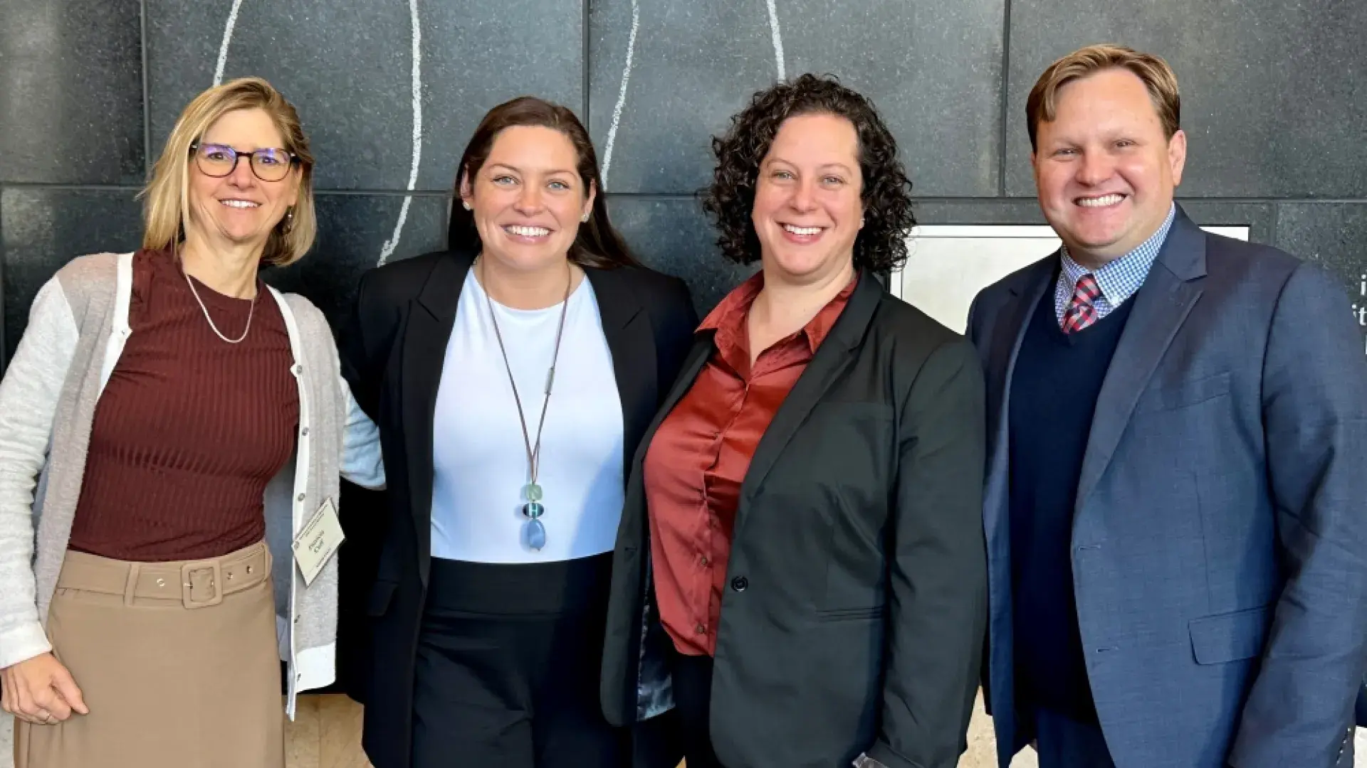 Four people standing and smiling